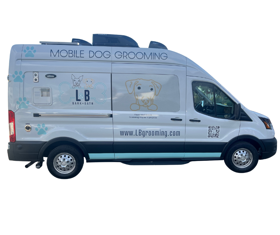 A white mobile dog grooming van with graphics of dogs, paw prints, and the company's website, www.LBgrooming.com.