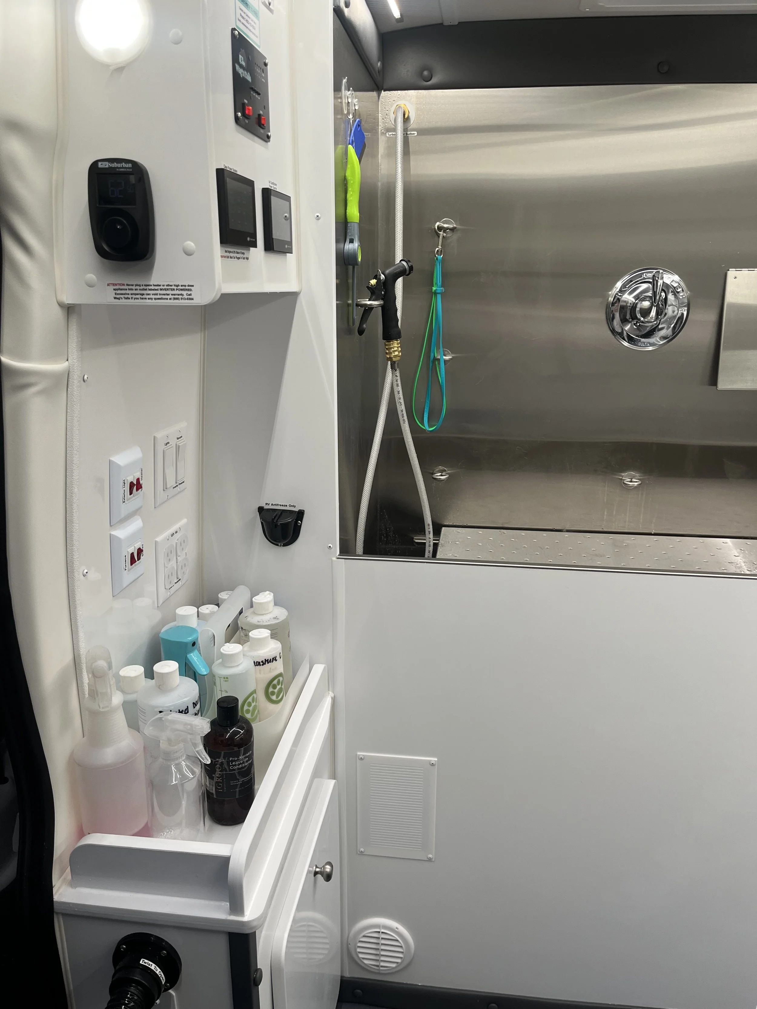 Interior of a mobile medical or veterinary sterilization unit with various cleaning and sterilization supplies, including bottles of disinfectant, spray bottles, and cleaning tools, adjacent to a stainless steel sterilization chamber with a door and 