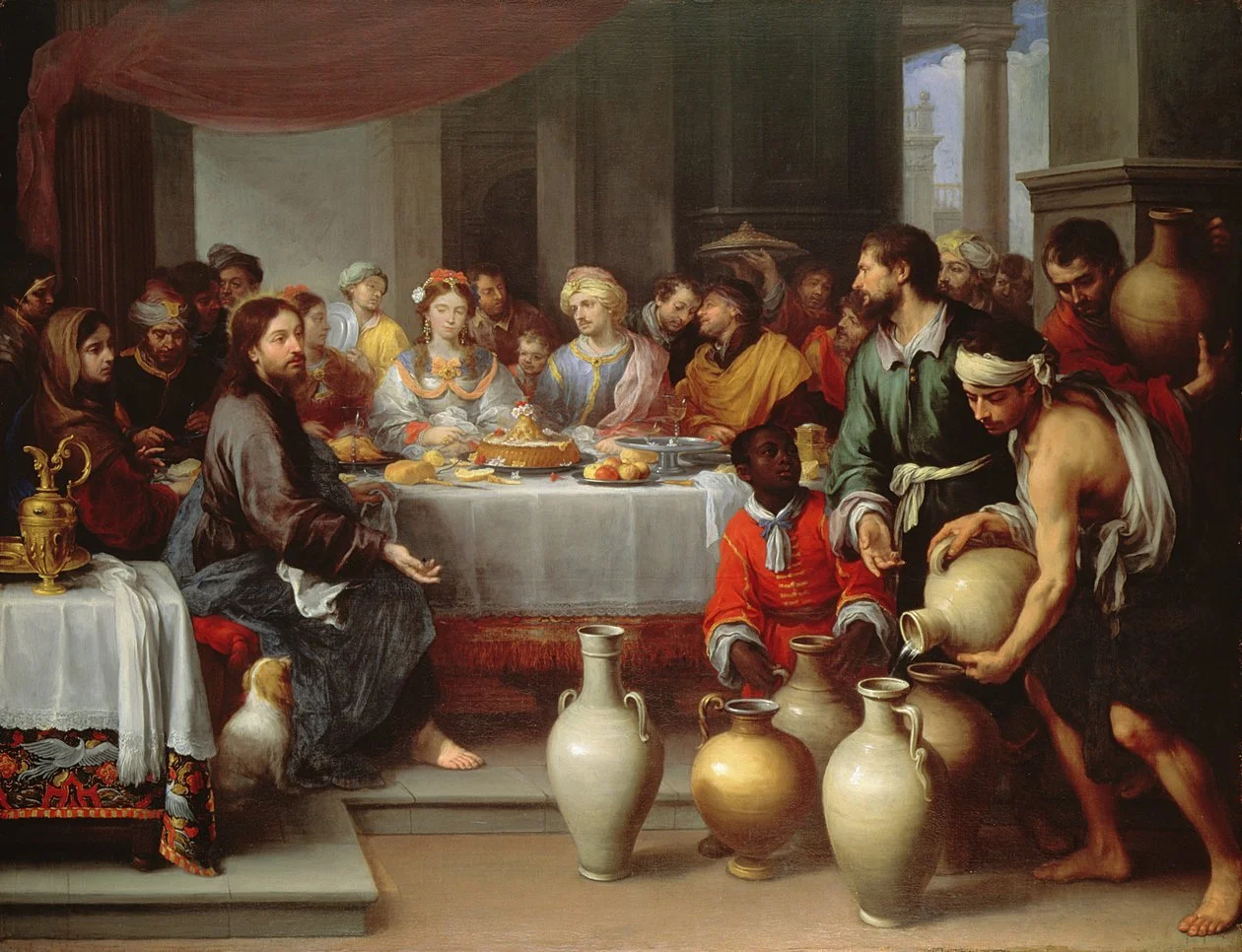 Recreación de la Última Cena, con Jesús y sus discípulos en una mesa, rodeados de personas y sirvientes con jarras y comida.