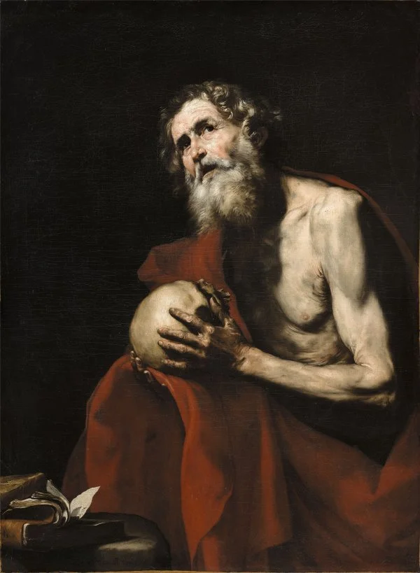 Retrato de un anciano con barba, piel delgada, con un paño rojo y sosteniendo un cráneo, en un fondo oscuro.