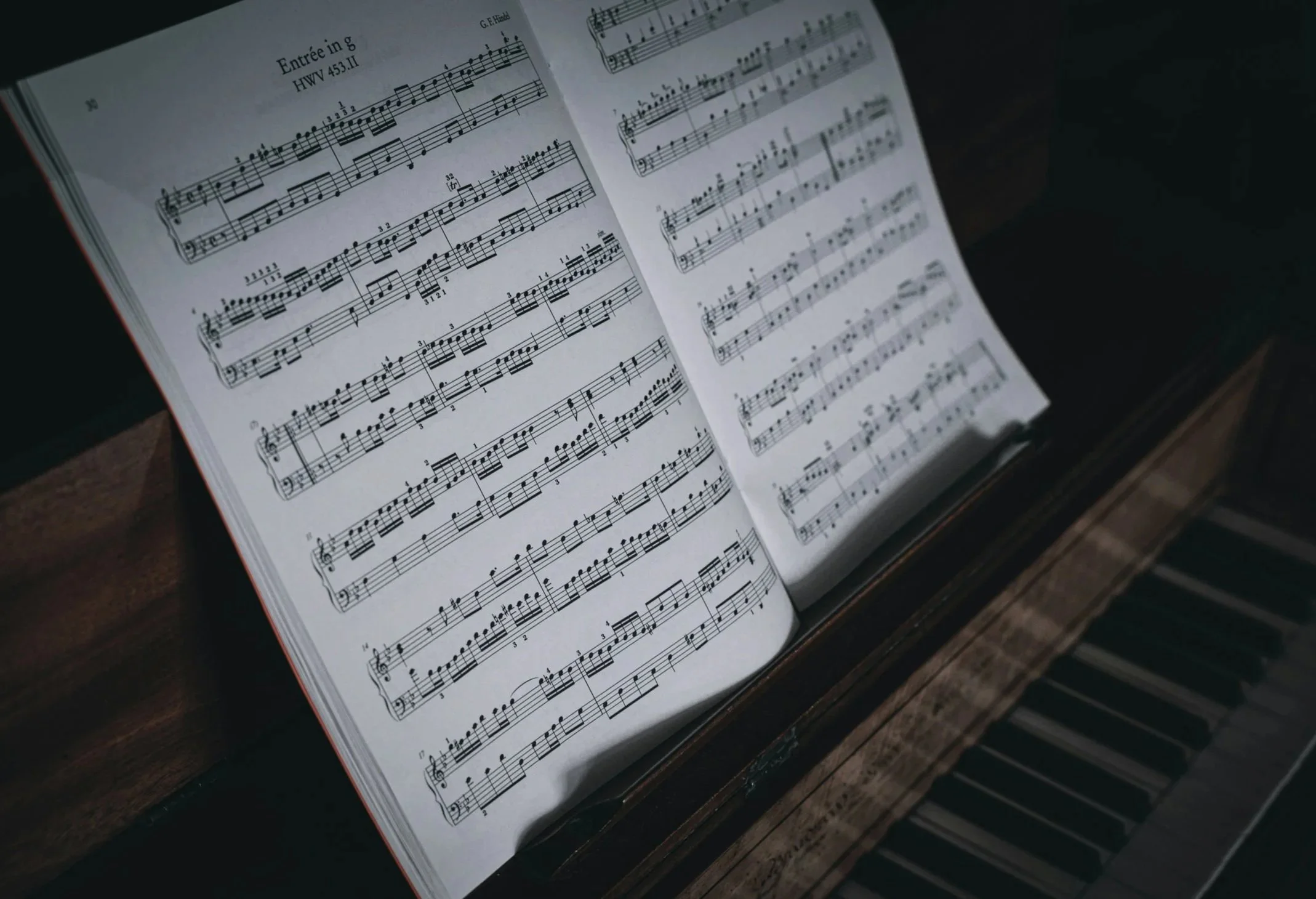 Partitura musical en un libro abierto sobre un piano, con notas y marcas de interpretación.