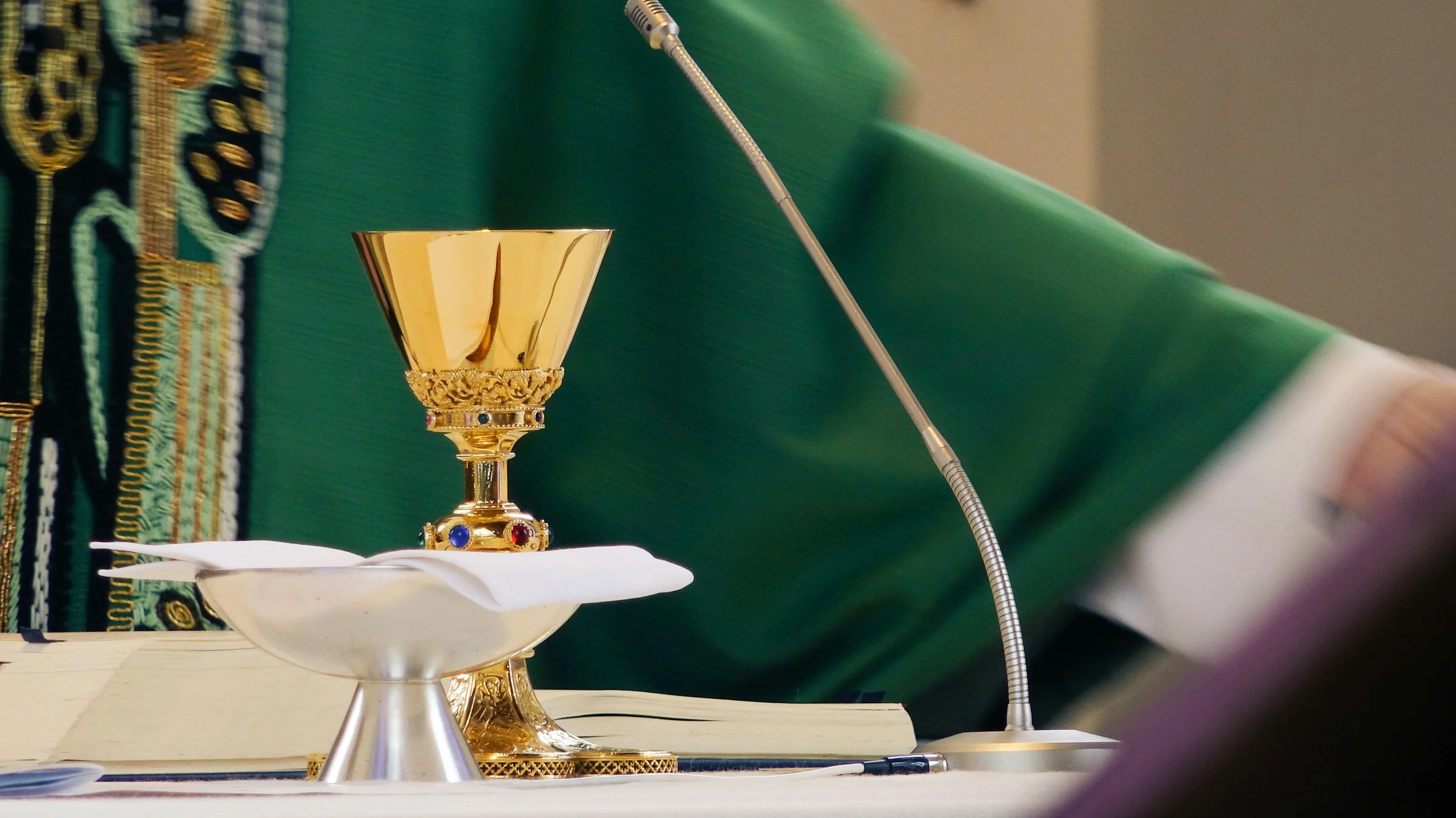 Copas, libro y micrófono sobre mesa en ceremonia religiosa