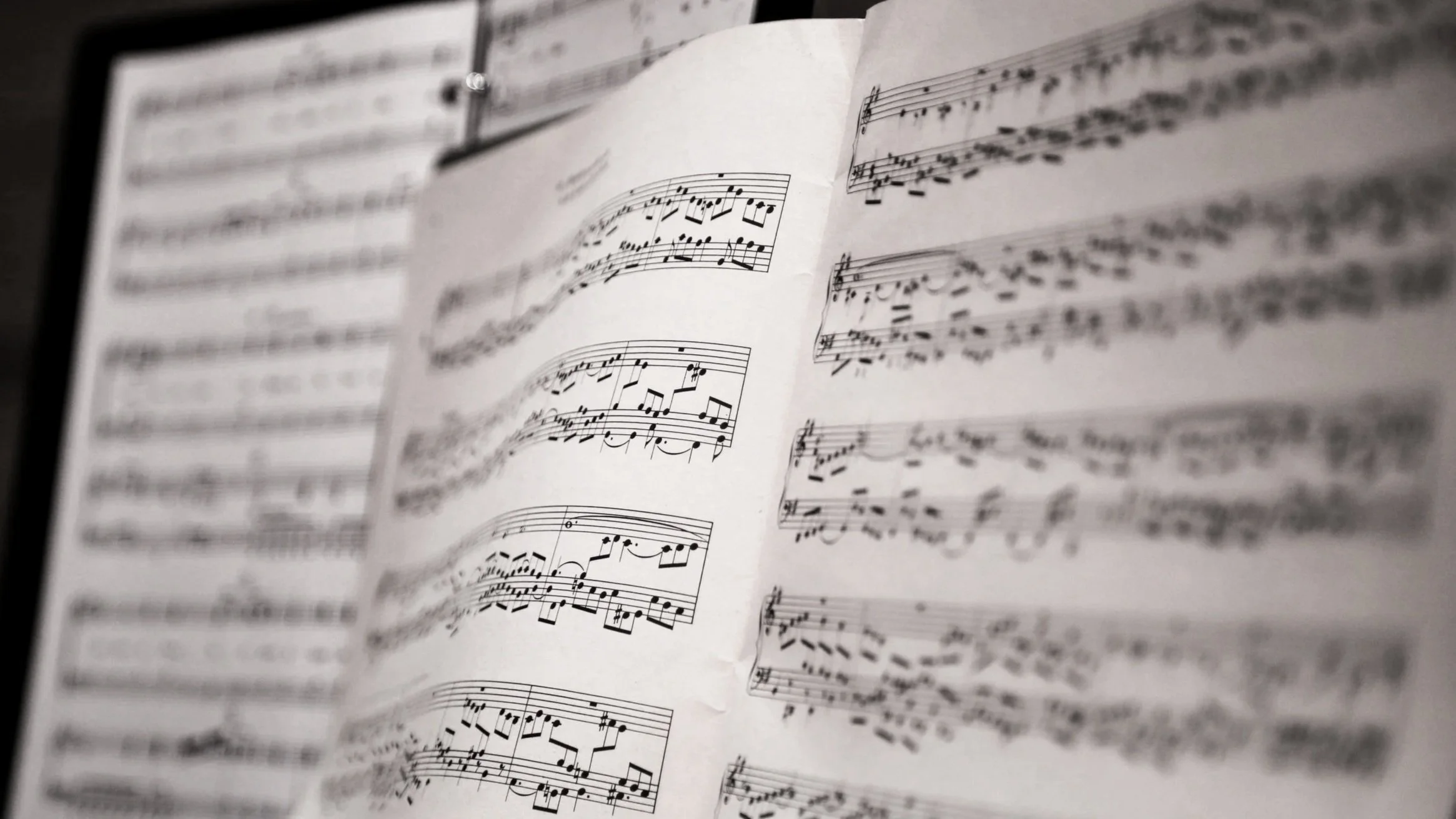 Partitura musical con notas y líneas en una hoja, en blanco y negro, en una carpeta de partituras.