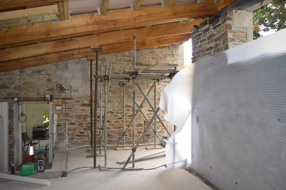 Under construction with scaffolding and wooden roof in a building with stone brick walls.