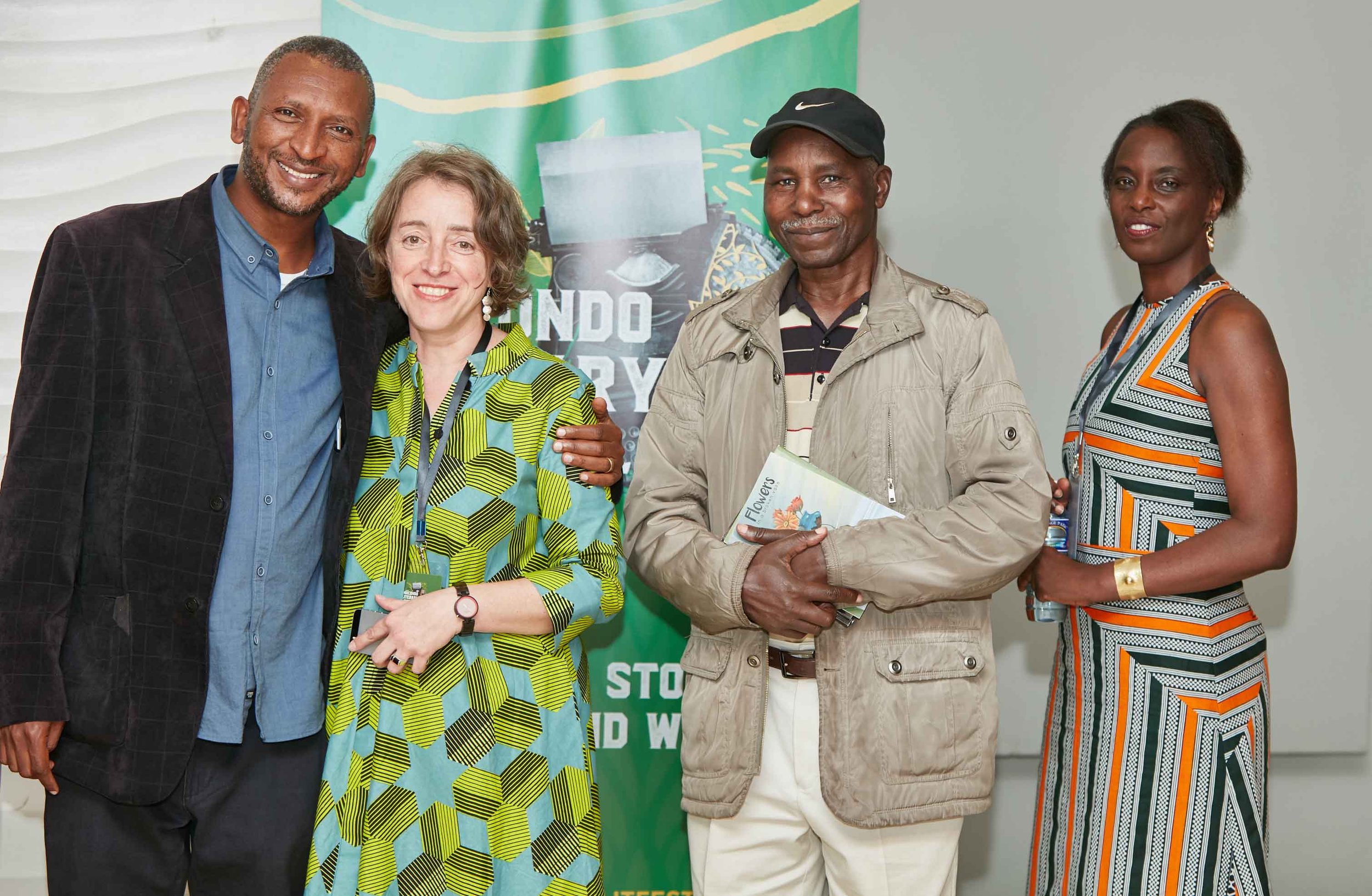 Four people standing together indoors for a photo, with a green banner in the background that reads 'ENDO' and 'RY' and a cartoonish graphic.