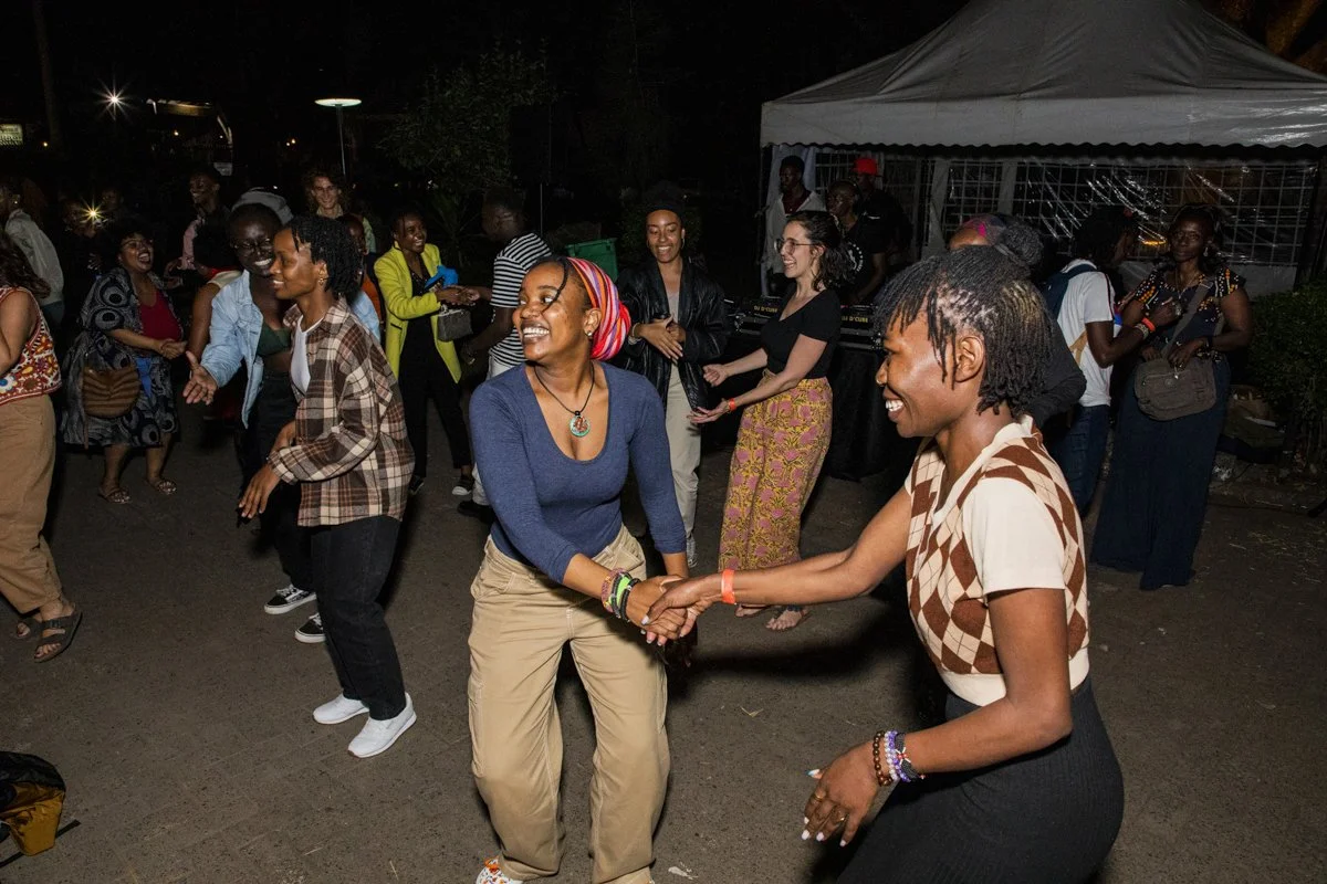 People dancing and socializing at an outdoor night event, some holding hands and smiling.