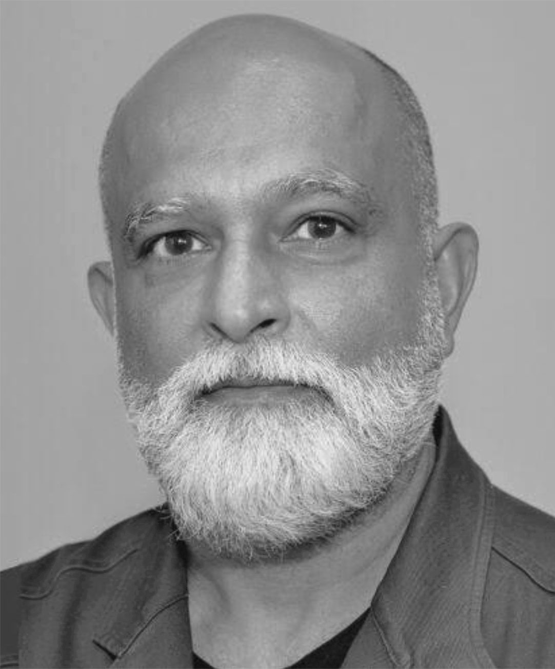 Black and white portrait of a man with a bald head and a full white beard, wearing a dark suit jacket.