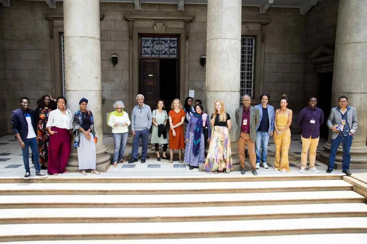 Group of diverse people standing on the steps of a building with large columns and stone facade.