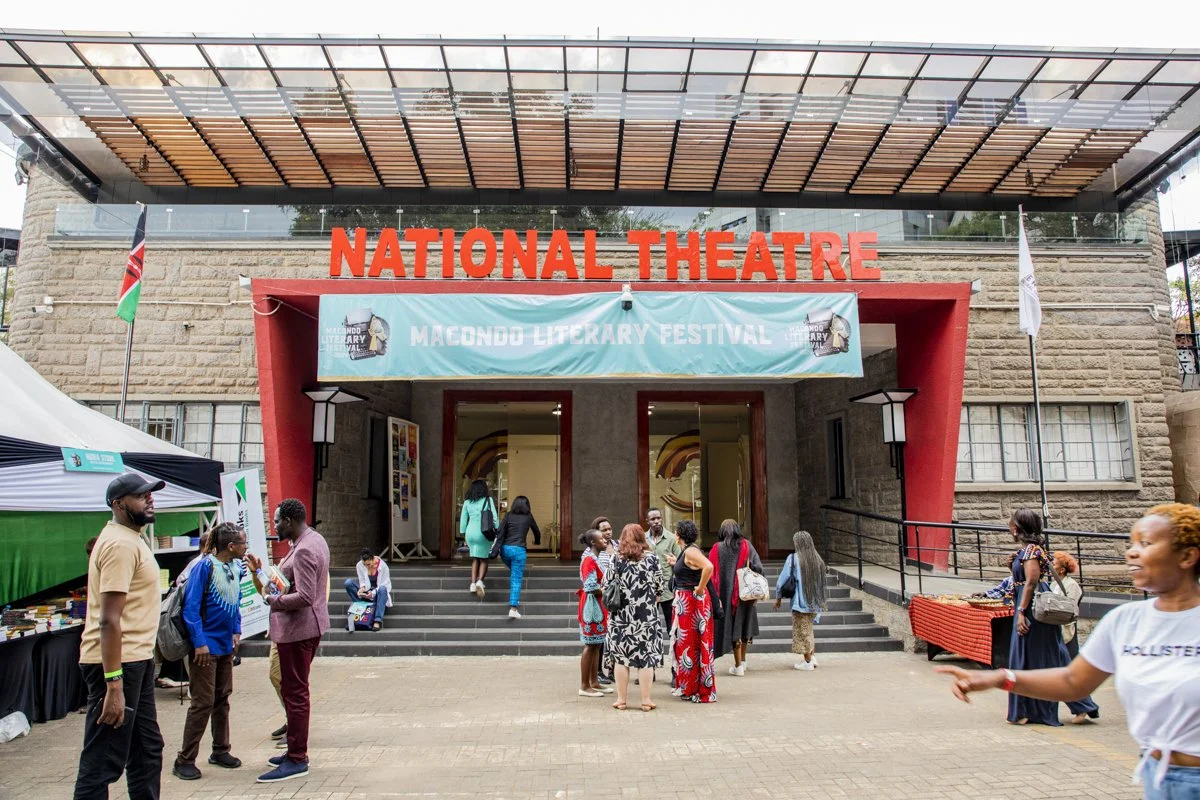 People gathering outside the National Theatre at the Macondo Literary Festival with a large banner and various stalls.