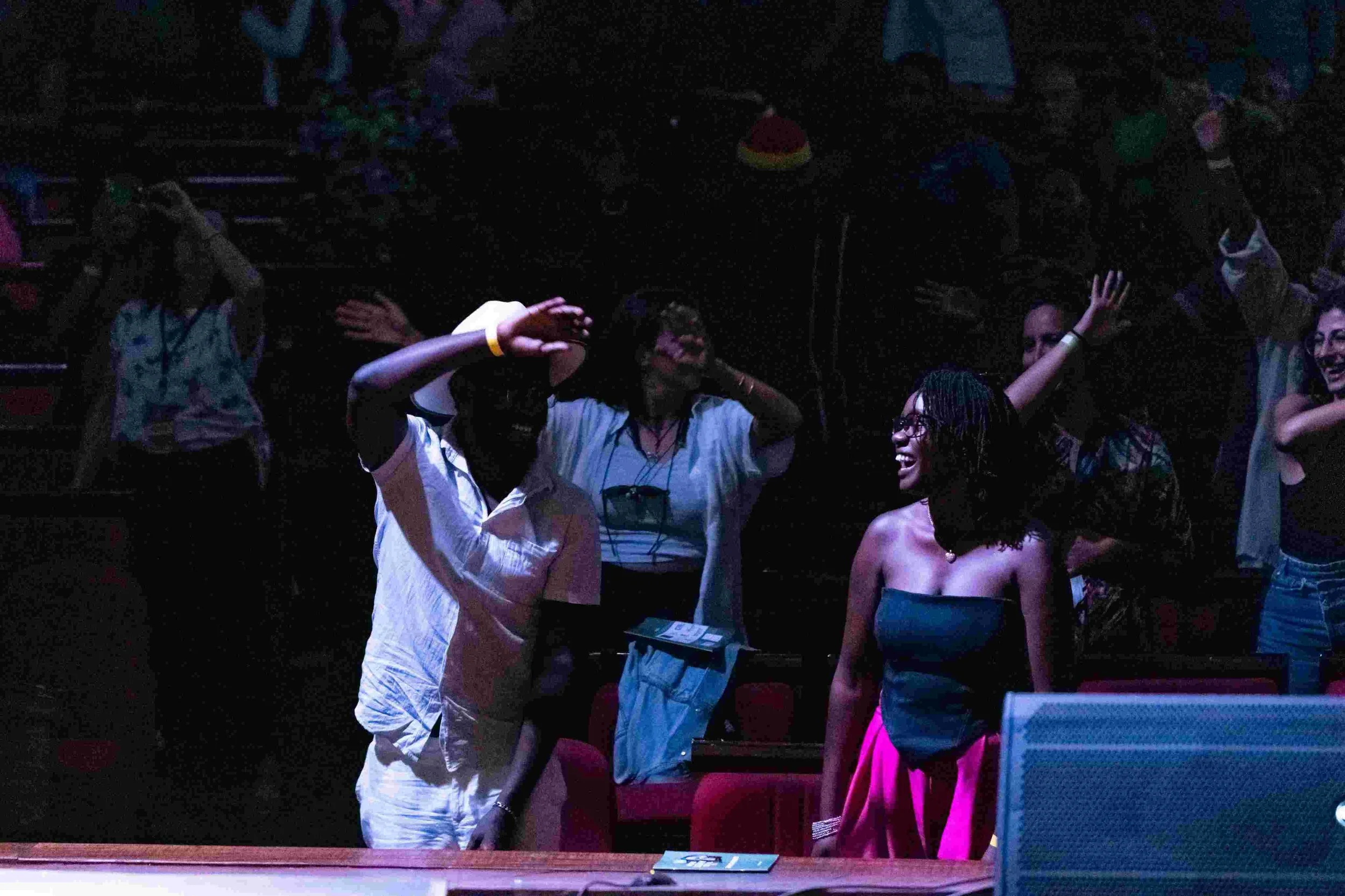 People in an auditorium laughing and engaging with each other during an event.