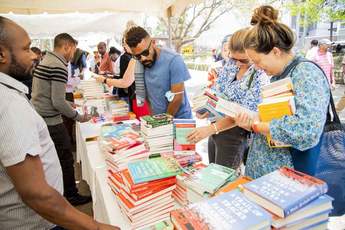 People browsing and buying books at an outdoor book market or fair.