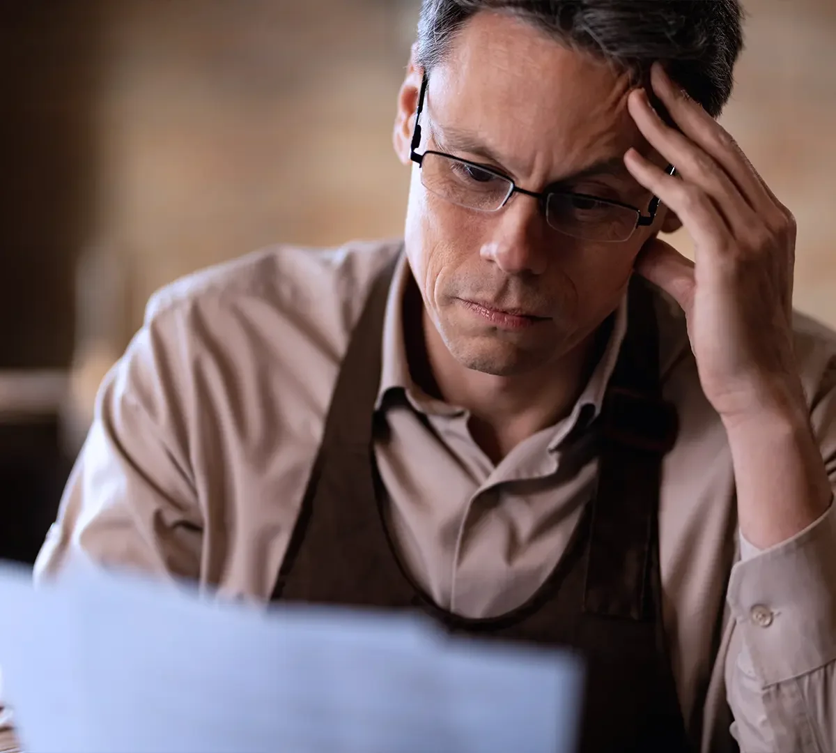 Mann mit Brille liest nachdenklich ein Dokument.