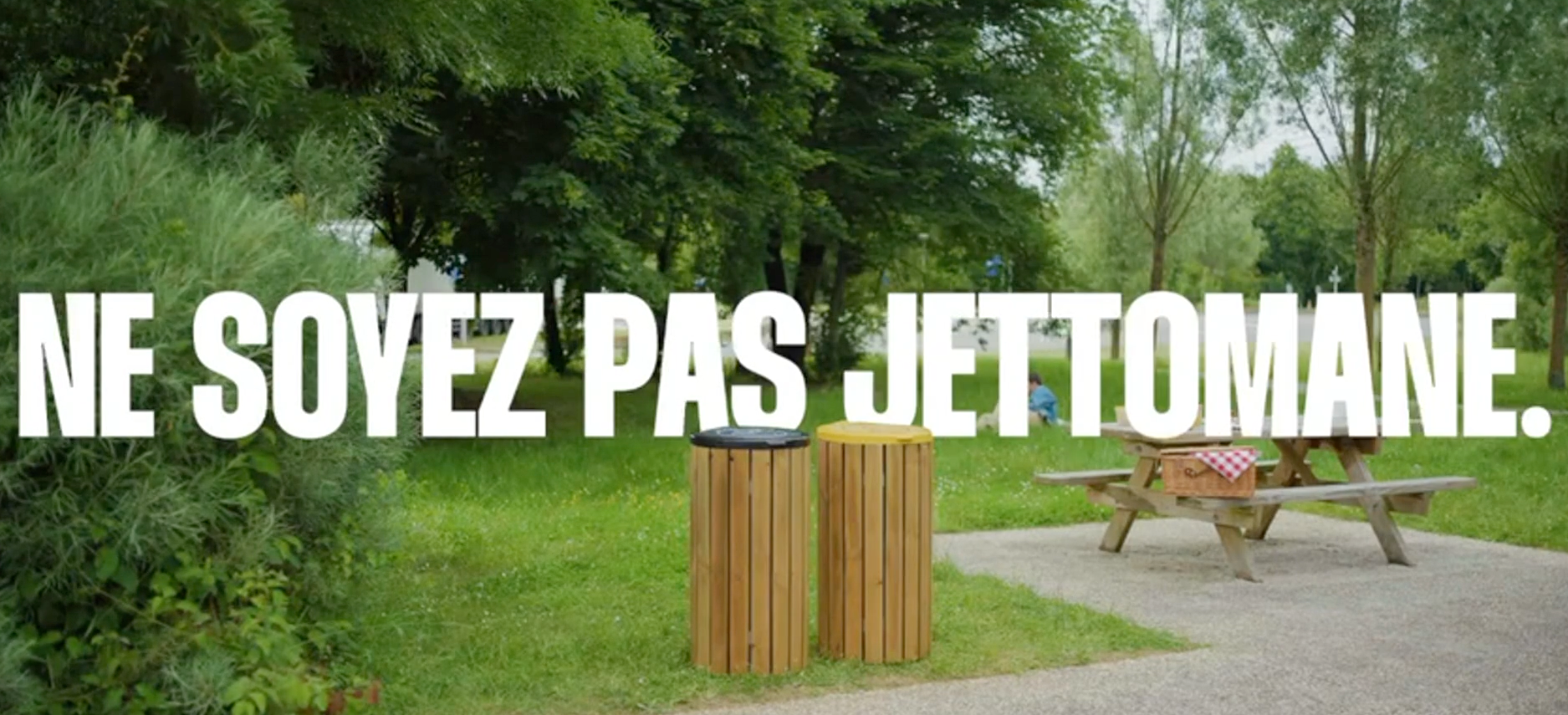 Parc verdoyant avec deux poubelles en bois et une table de pique-nique, accompagné du texte « NE SOYEZ PAS JETOMANE. »
