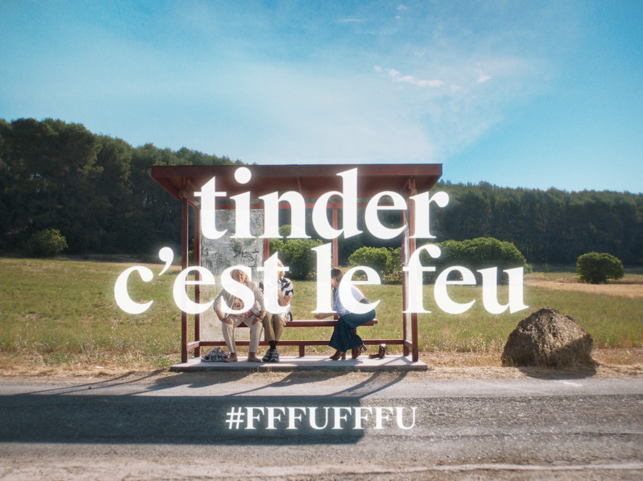 Trois personnes assises à un arrêt de bus champêtre, avec le texte « Indeed c’est l’été » et le hashtag #FFFUFFFU.