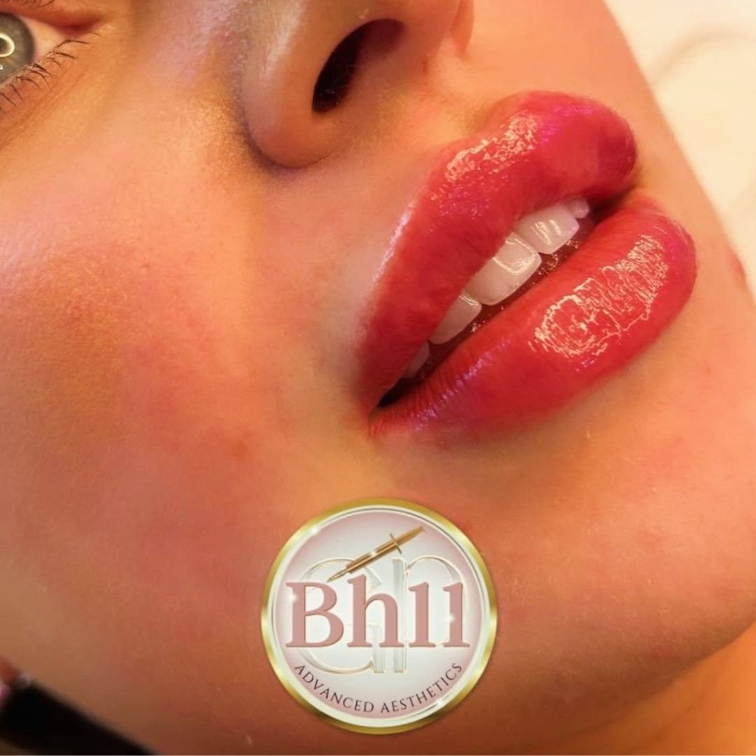 Close-up of a person's lips with red, glossy lipstick, partially open revealing teeth, and a small portion of the nose and cheek visible, with a logo that reads 'Bhi Advanced Aesthetics' at the bottom.