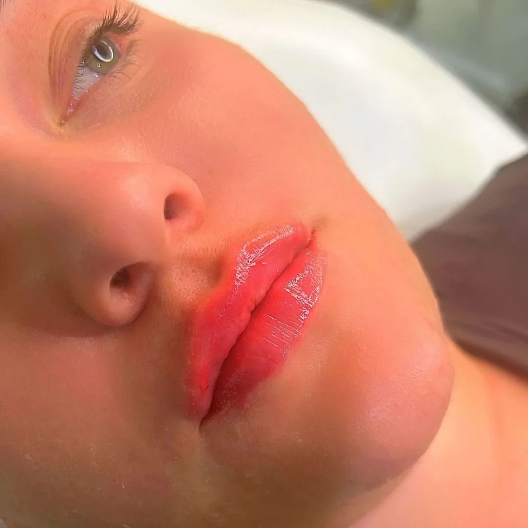Close-up of a person's face showing an eye, nose, lips with lipstick, and smooth skin.