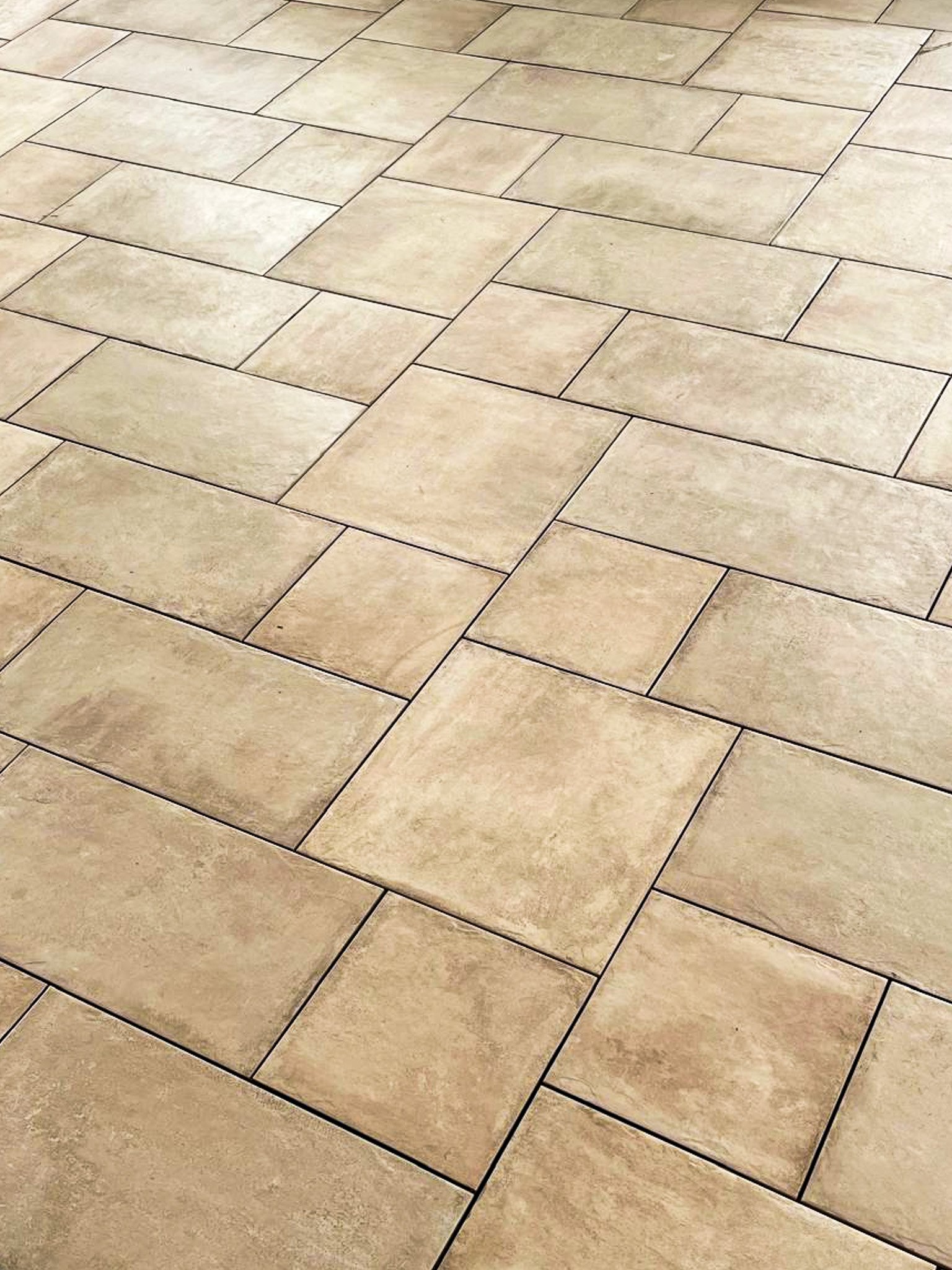 Carrelage en pierre beige posé en motif rectangulaire.