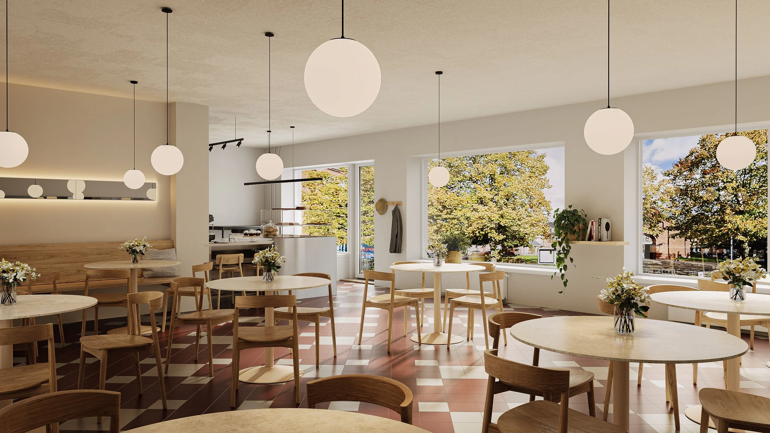 Indendørs café med træborde og -stole, store vinduer med udsigt til træer, hvide vægge og diskrete belysning, blomsterdekorationer på borde.