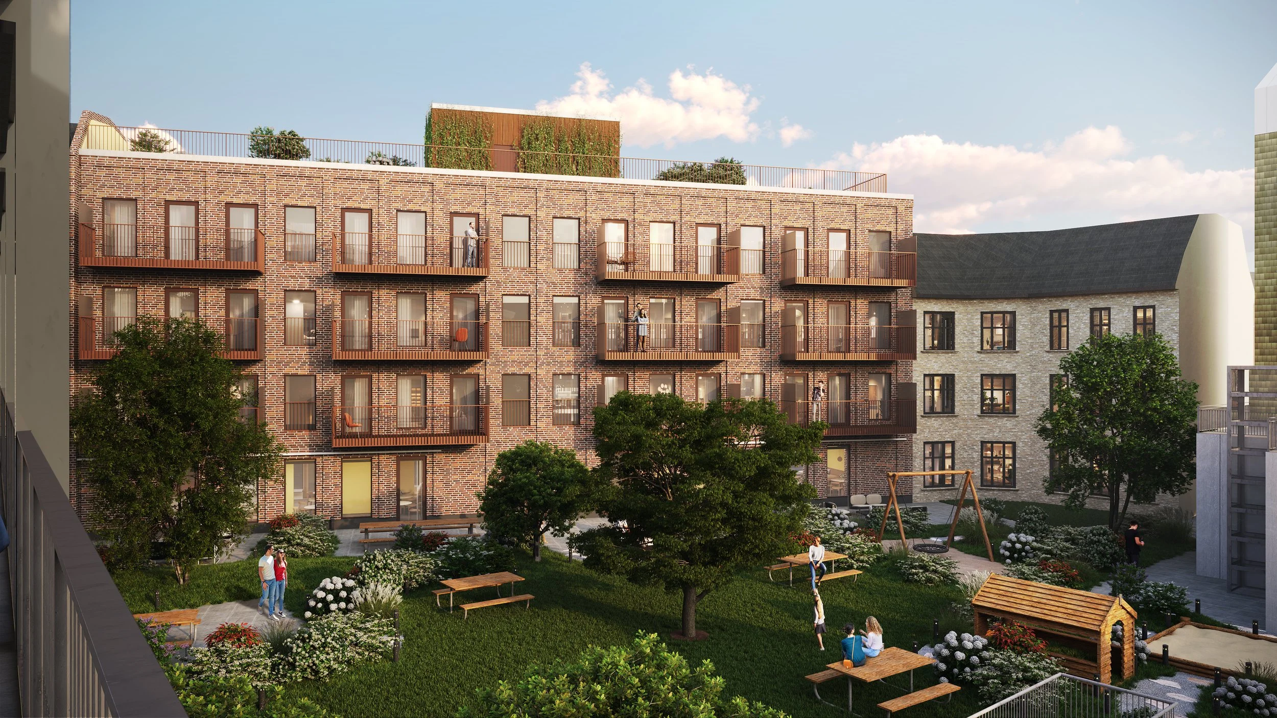 Udsigt over en grøn gård med legetøj, borde, træer og mennesker, omgivet af boligbygninger i sten og murværk med balkoner.