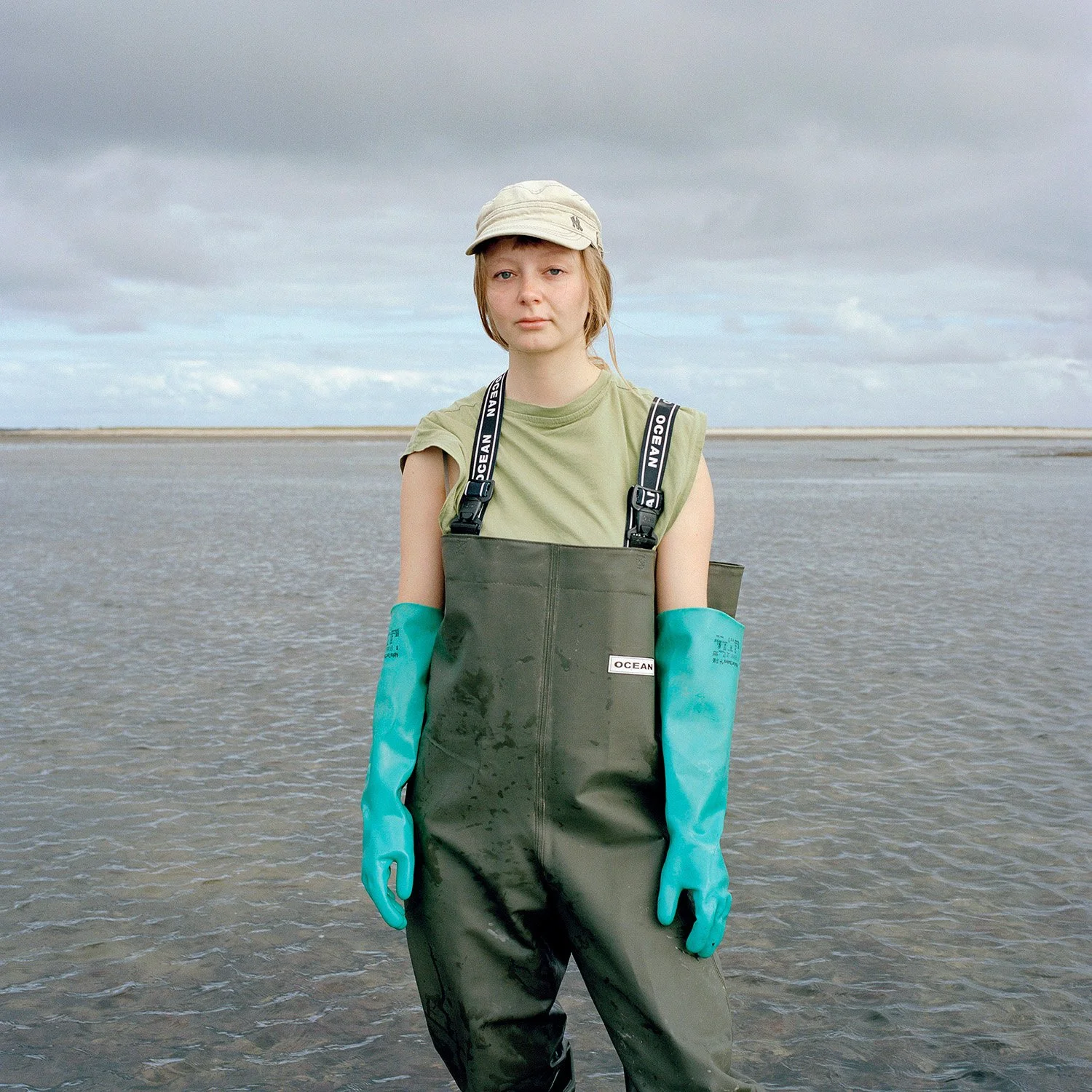 Leon Düllber  im Watt Frau im Wattenmeer Meer mit Handschuhen und Fischerhose und Mütze wolkiger Himmel