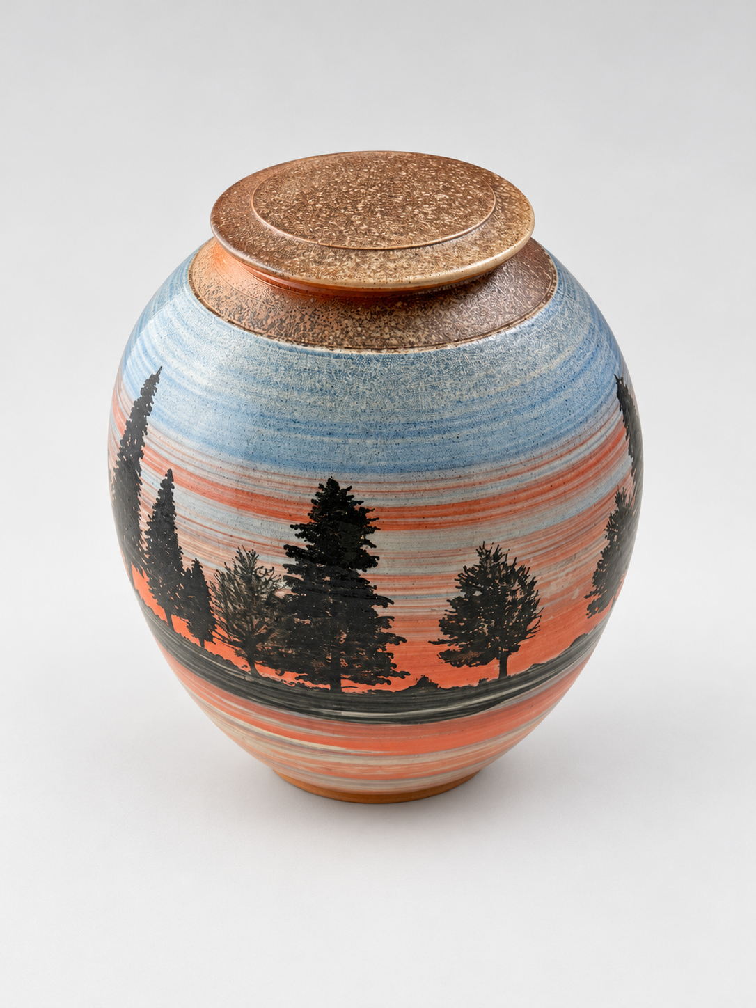 Handcrafted lidded stoneware jar featuring silhouetted pine trees against a blue and coral sunset landscape. One-of-a-kind pottery by Chad Jerzak.