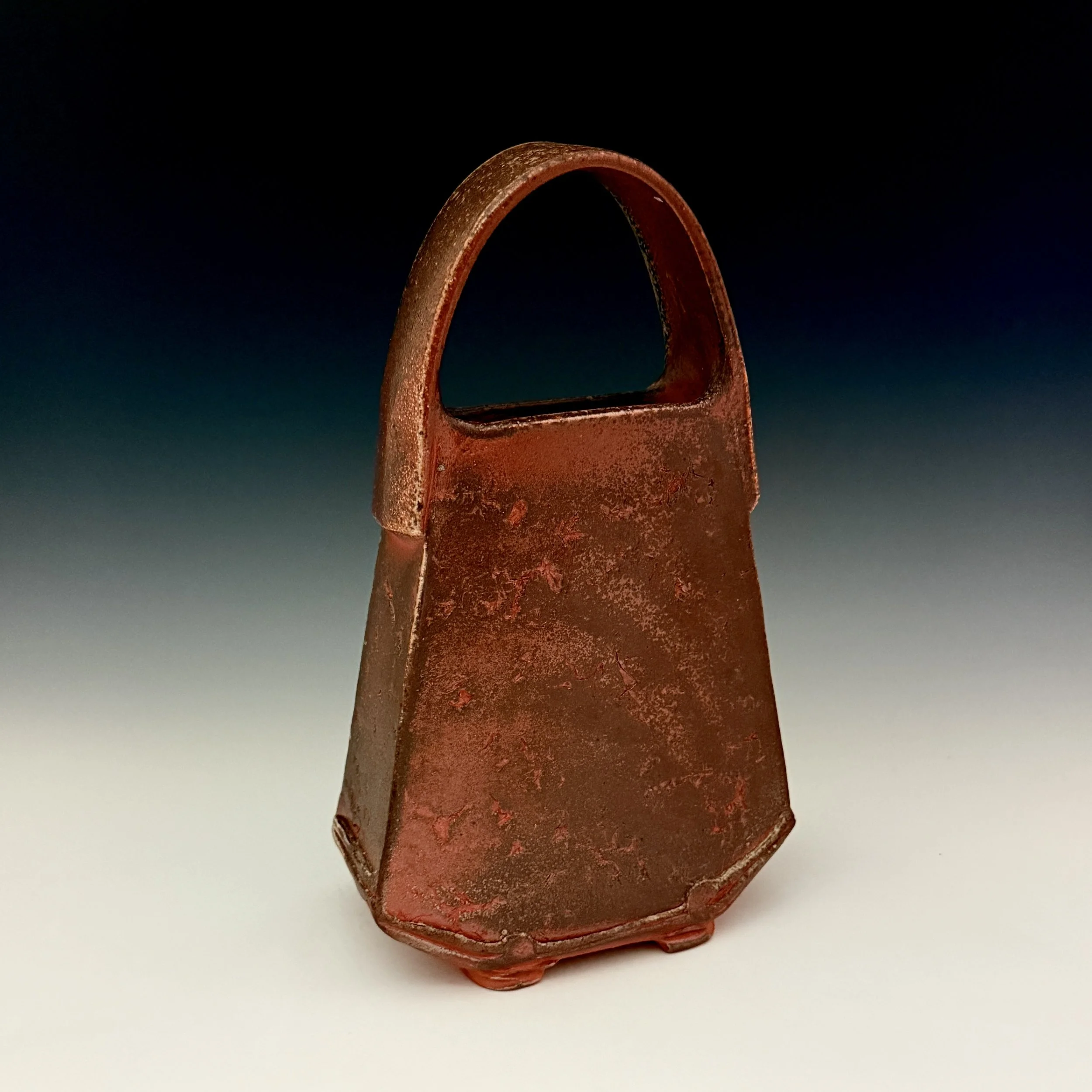 Rusty, metal helmet with a handle on top, set against a dark background.