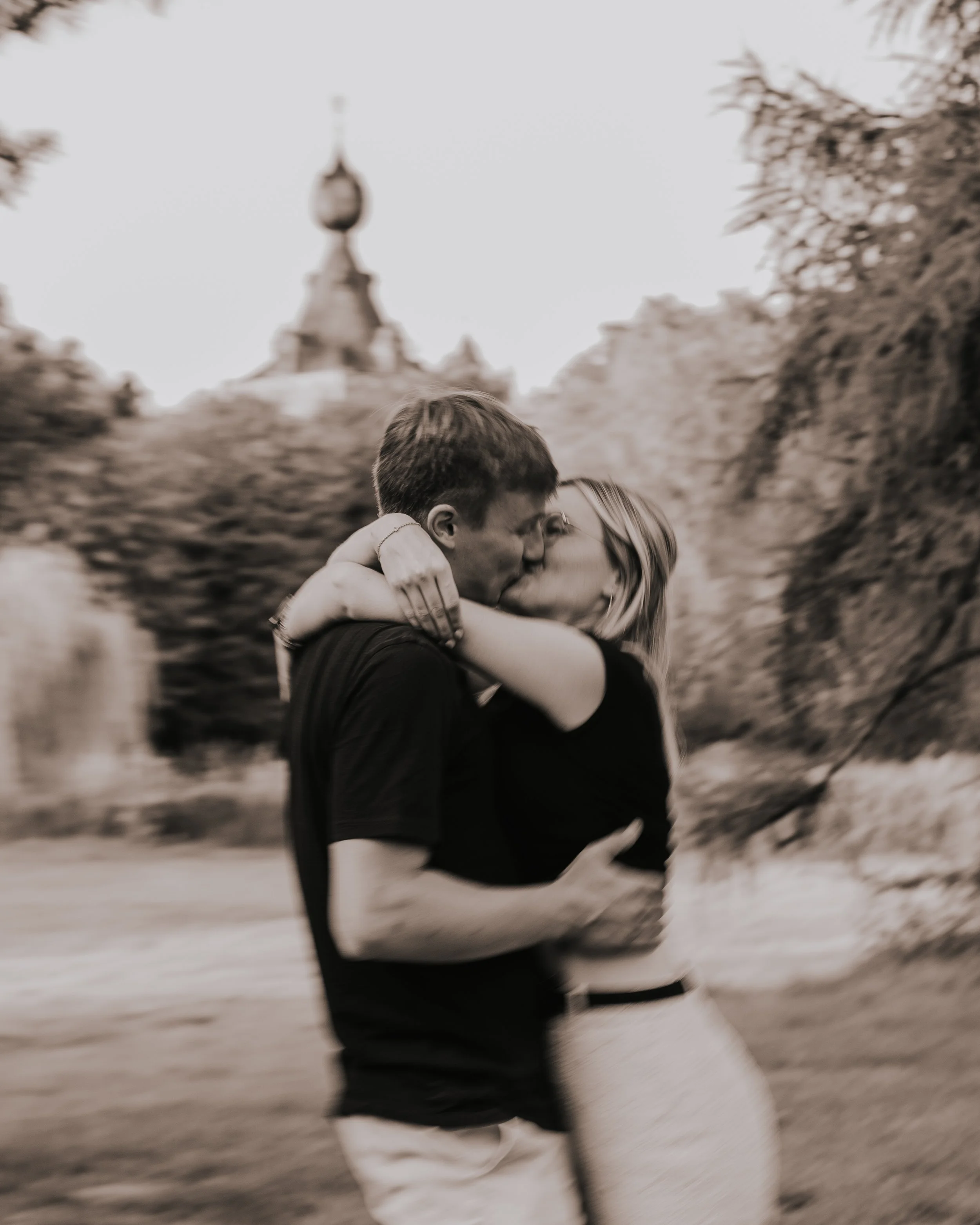 Twee mensen kussen elkaar liefdevol in een park.