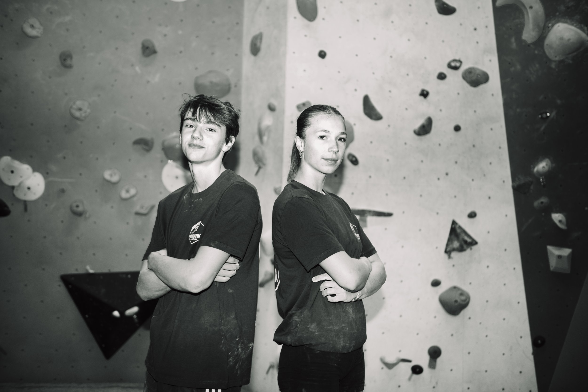 Twee jonge klimploegers staan met gekruiste armen in een klimhal, zwart-wit foto.