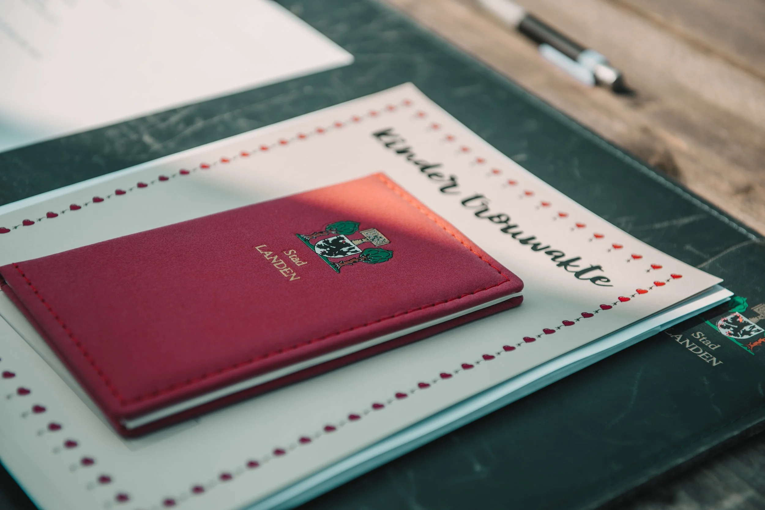 Een agenda met het stadswapen van Stad Landen ligt op een tafel, daarnaast ligt een map en een pen.