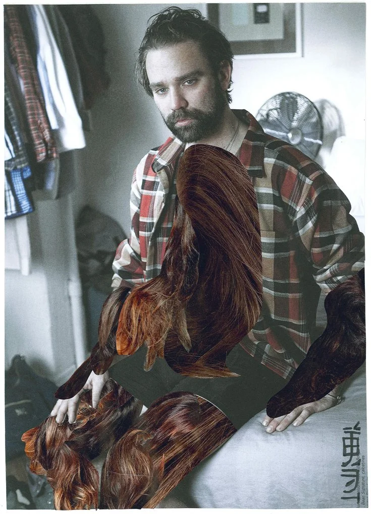 A man with dark hair and a beard wearing a plaid shirt, leaning over a table with disassembled and overlapping sections of long, auburn hair in a room with a fan and clothing hanging in the background.