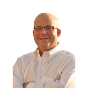 A bald man wearing glasses and a white dress shirt, smiling with arms crossed, against a plain white background.