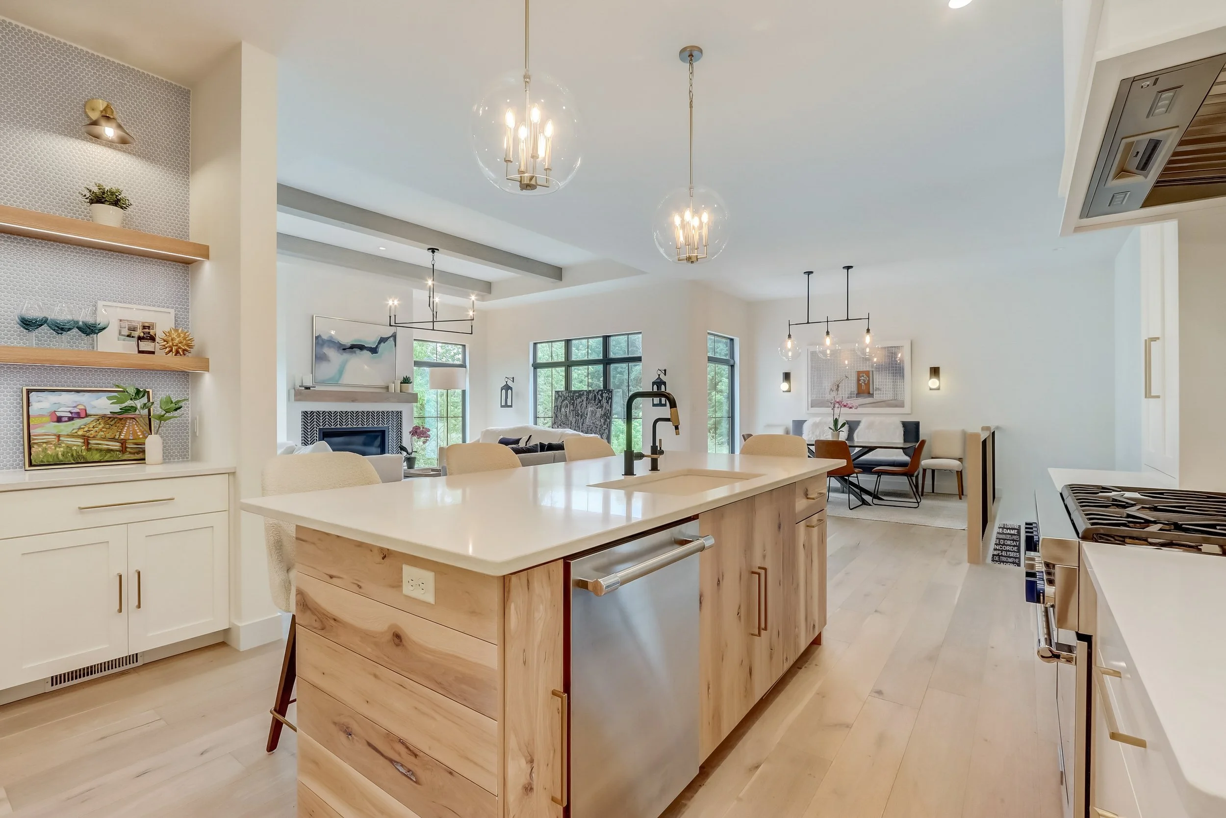 Open-concept kitchen and living room with a central island, modern lighting, and large windows
