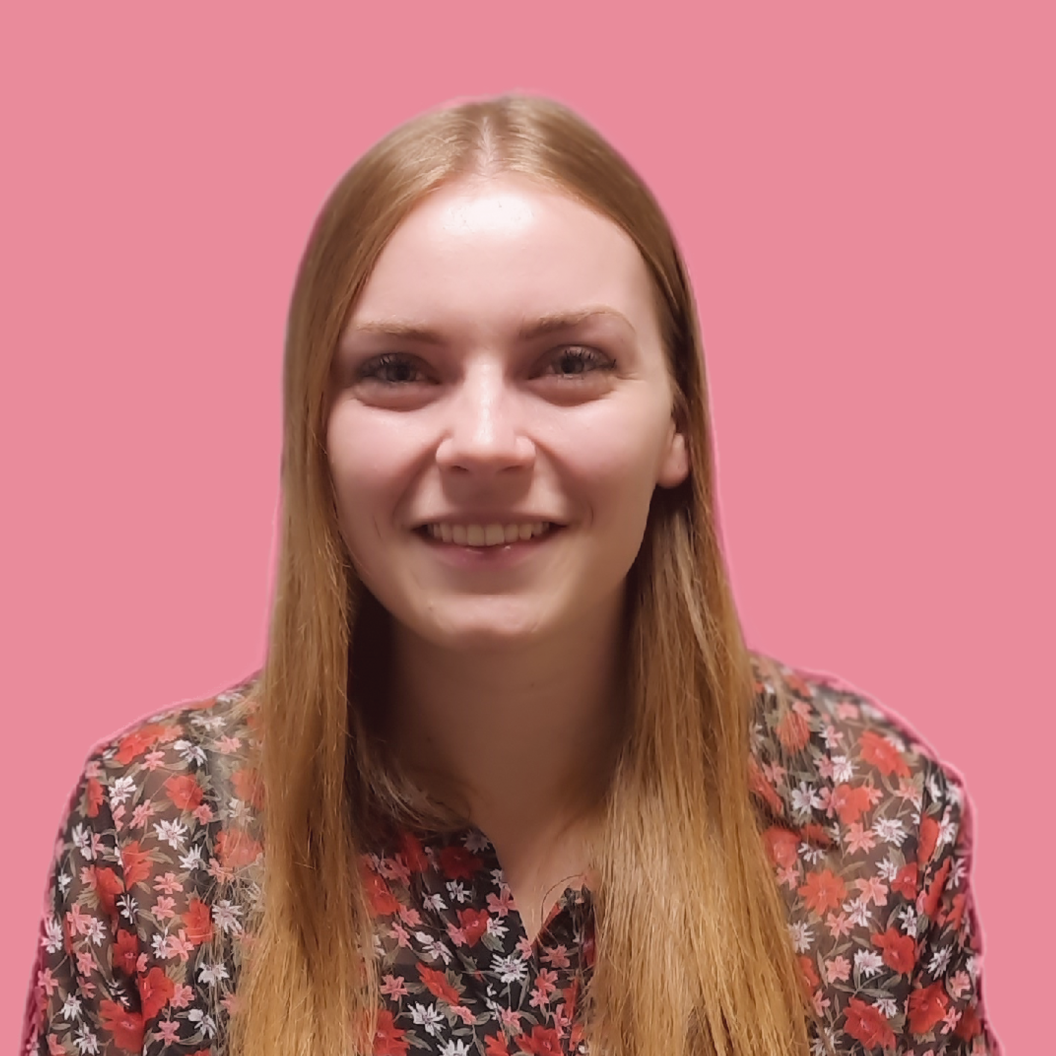 Portret van een vrouw met lang rood haar, lachend, tegen een roze achtergrond.