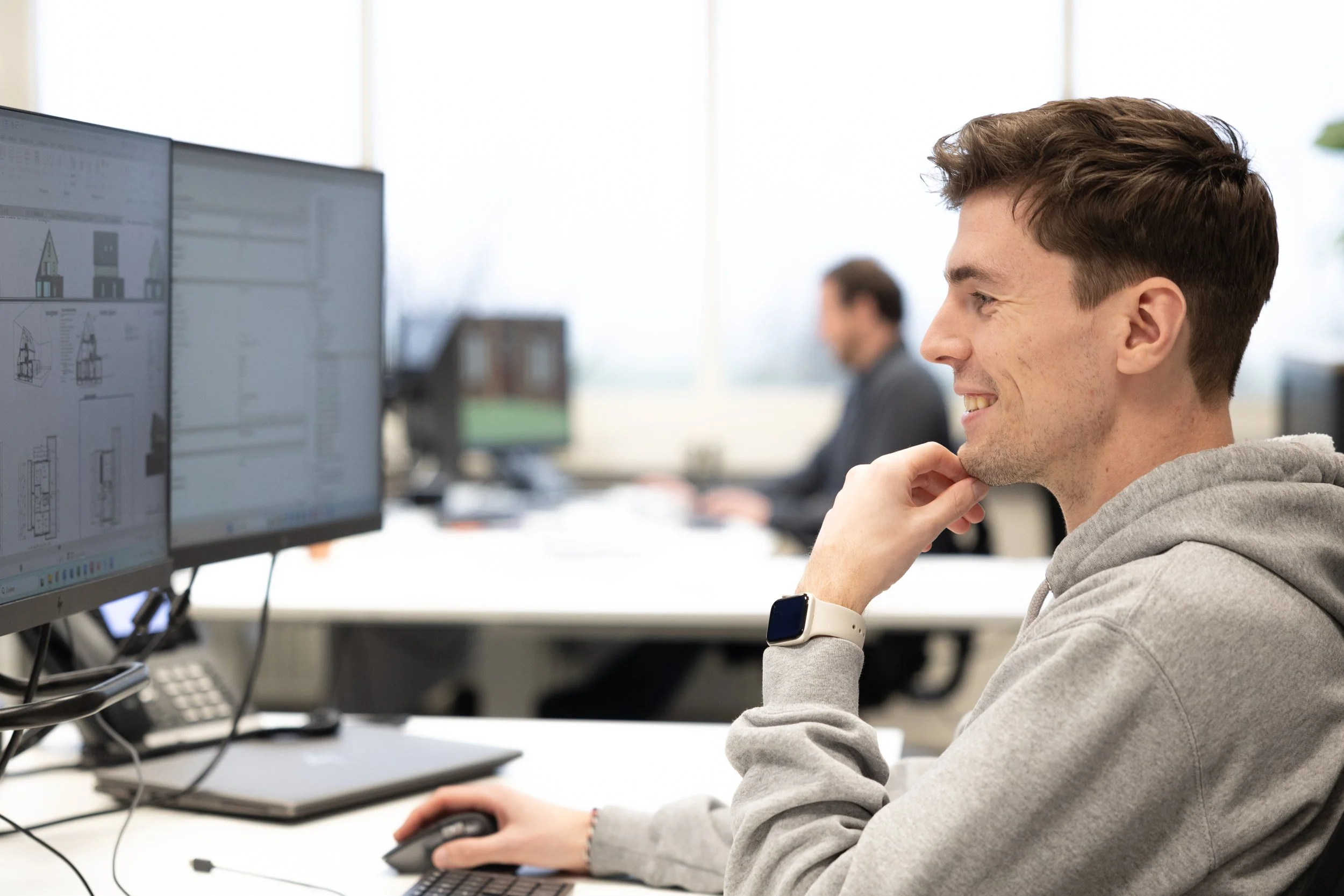 Man werkt op een computer met dual monitors in een kantoor.