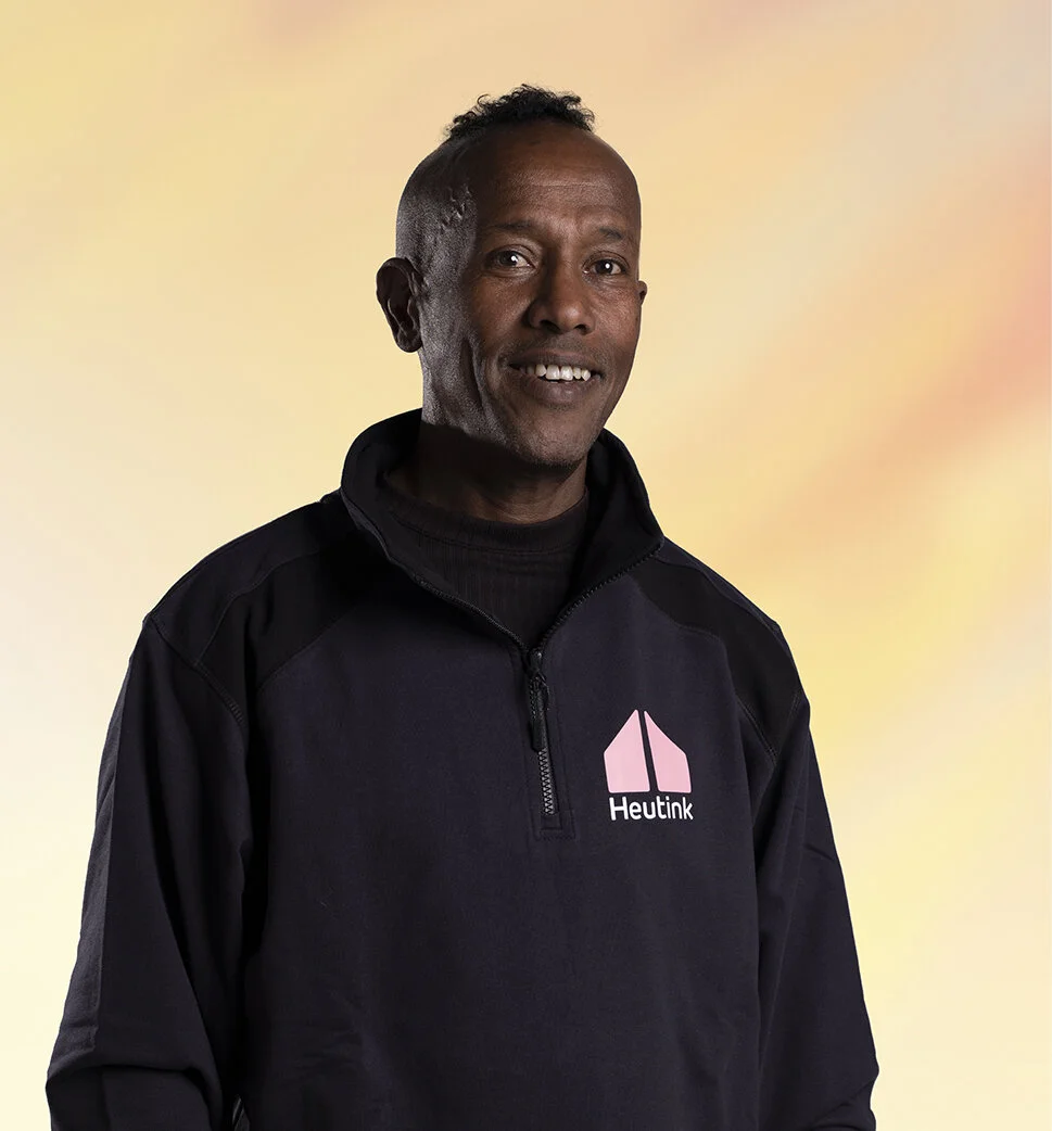 Man in zwart vest met 'Heutink' logo, lichte achtergrond.