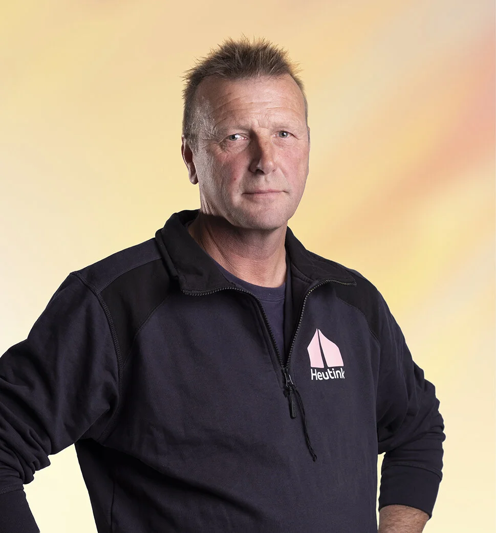 Man met korte, spiky haar, draagt een zwarte jas met een logo van Heutink.