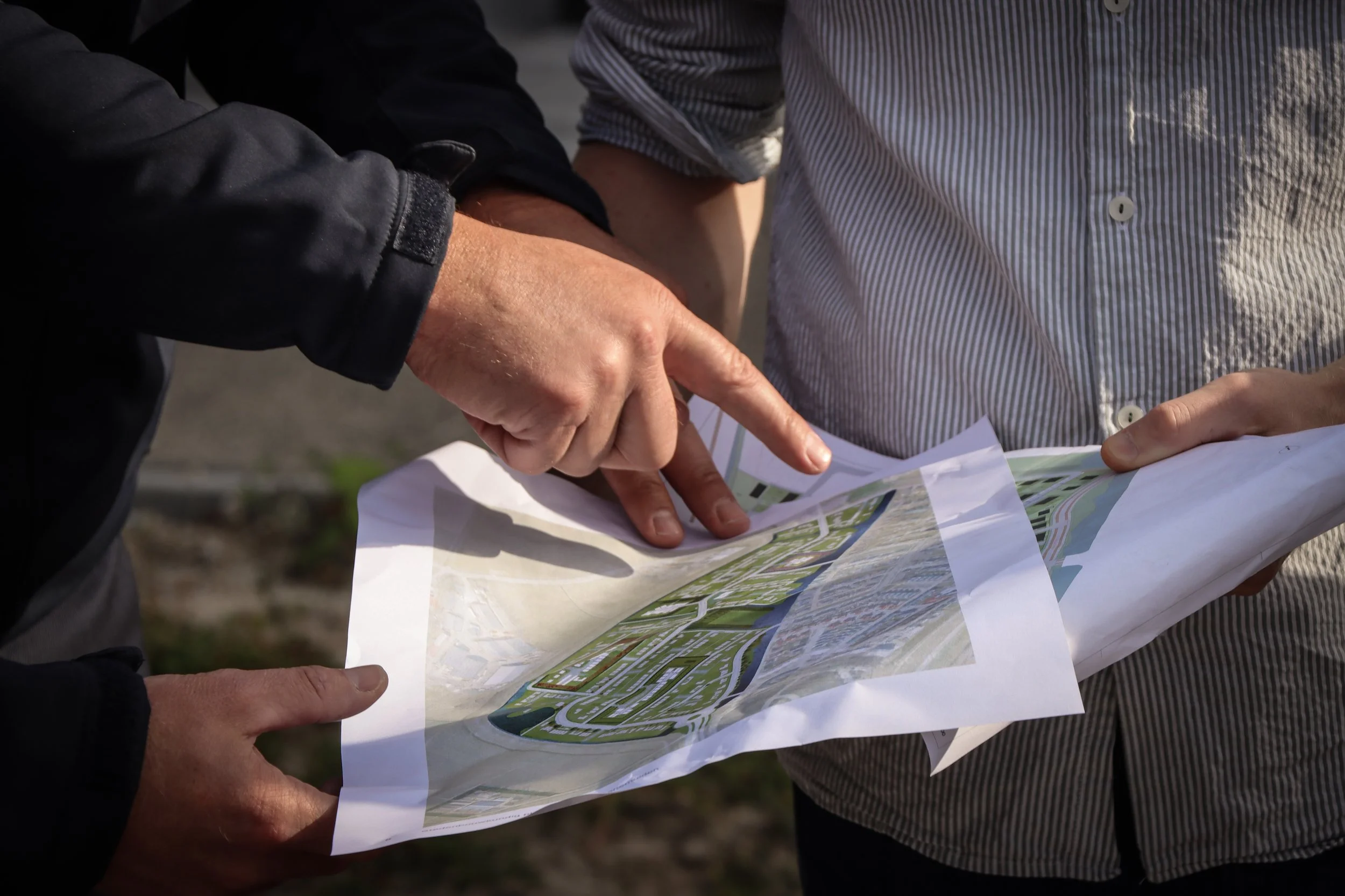 Twee personen die samenwerken en een plattegrond bekijken, mogelijk bij het plannen van een project of locatie op een buitengebied.
