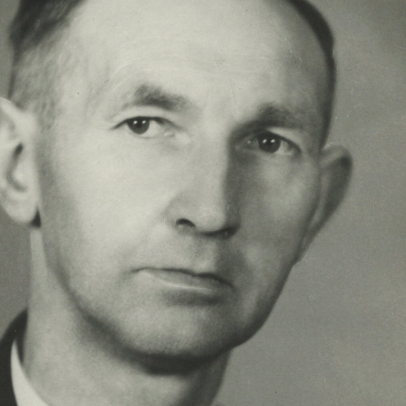 Zwart-wit portret van een jonge man met korte haar, lichte huid en strakke kleding, kijkend naar de camera.