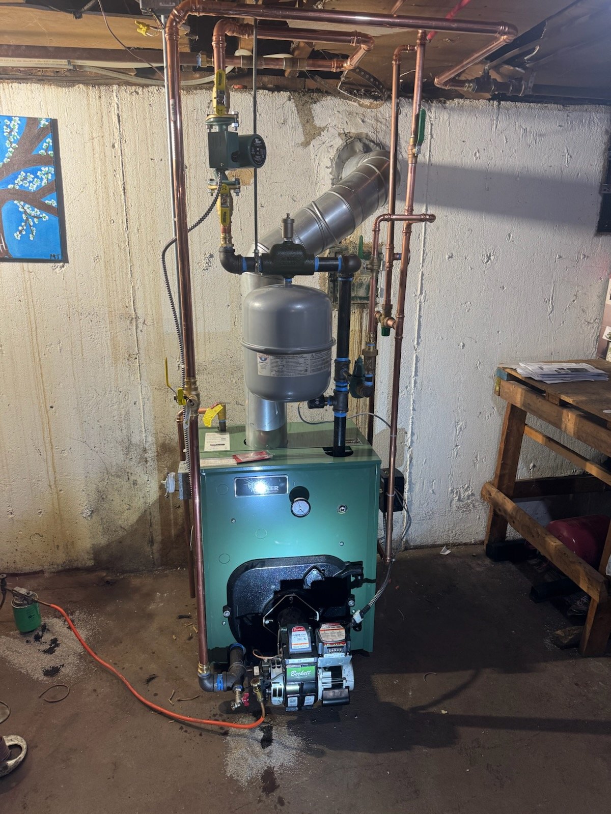 A furnace in a basement with copper pipes, a vent, and a pump.