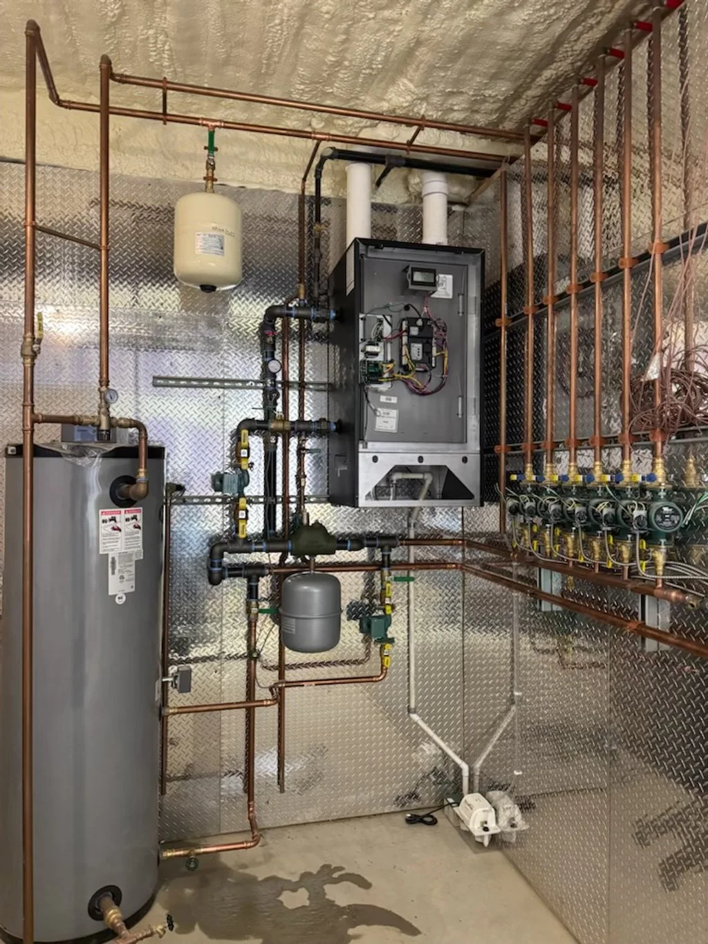 A utility room with various pipes, gauges, and a water heater.