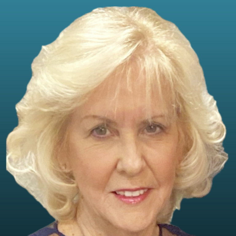 Close-up portrait of a smiling blonde woman with short hair and blue eyes, wearing a dark top, against a teal background.