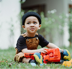 A boy sitting outside with a toy