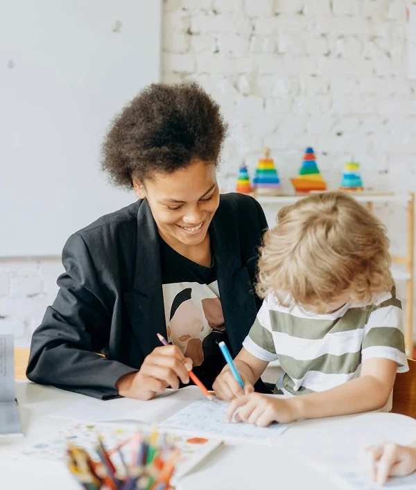 A woman supervising a child writing