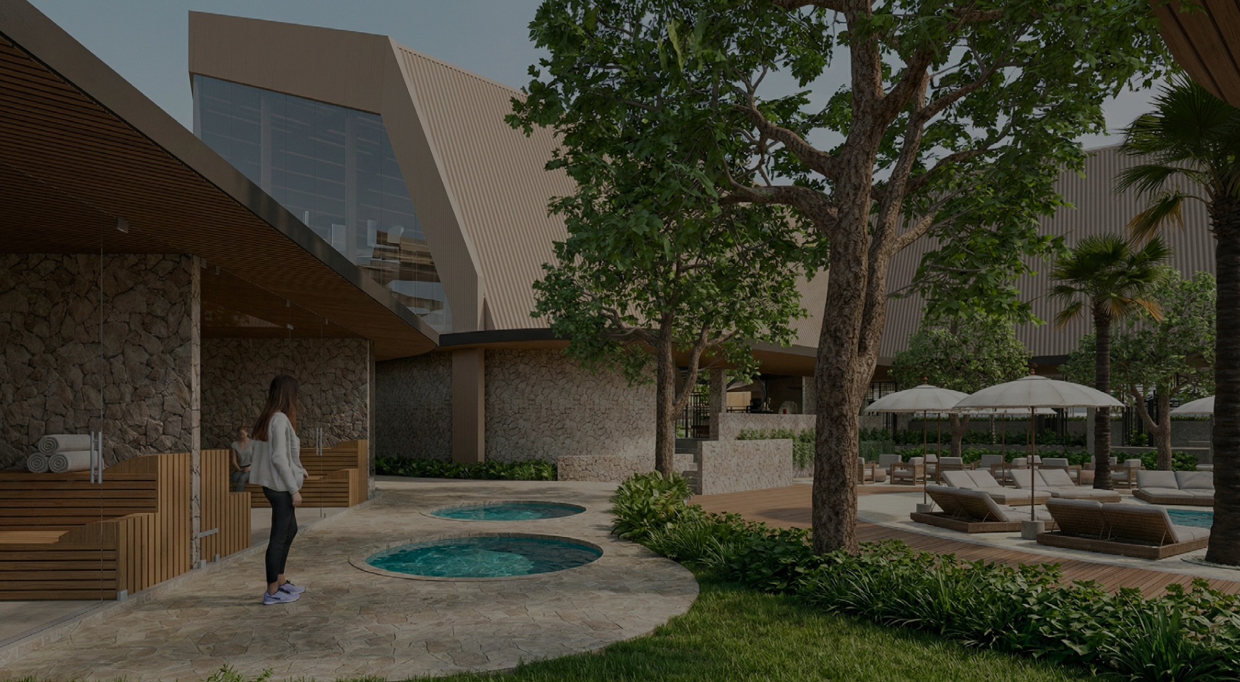 An aerial view of a swimming pool with a person floating on their back, surrounded by lounge chairs and umbrellas, with greenery and trees around.