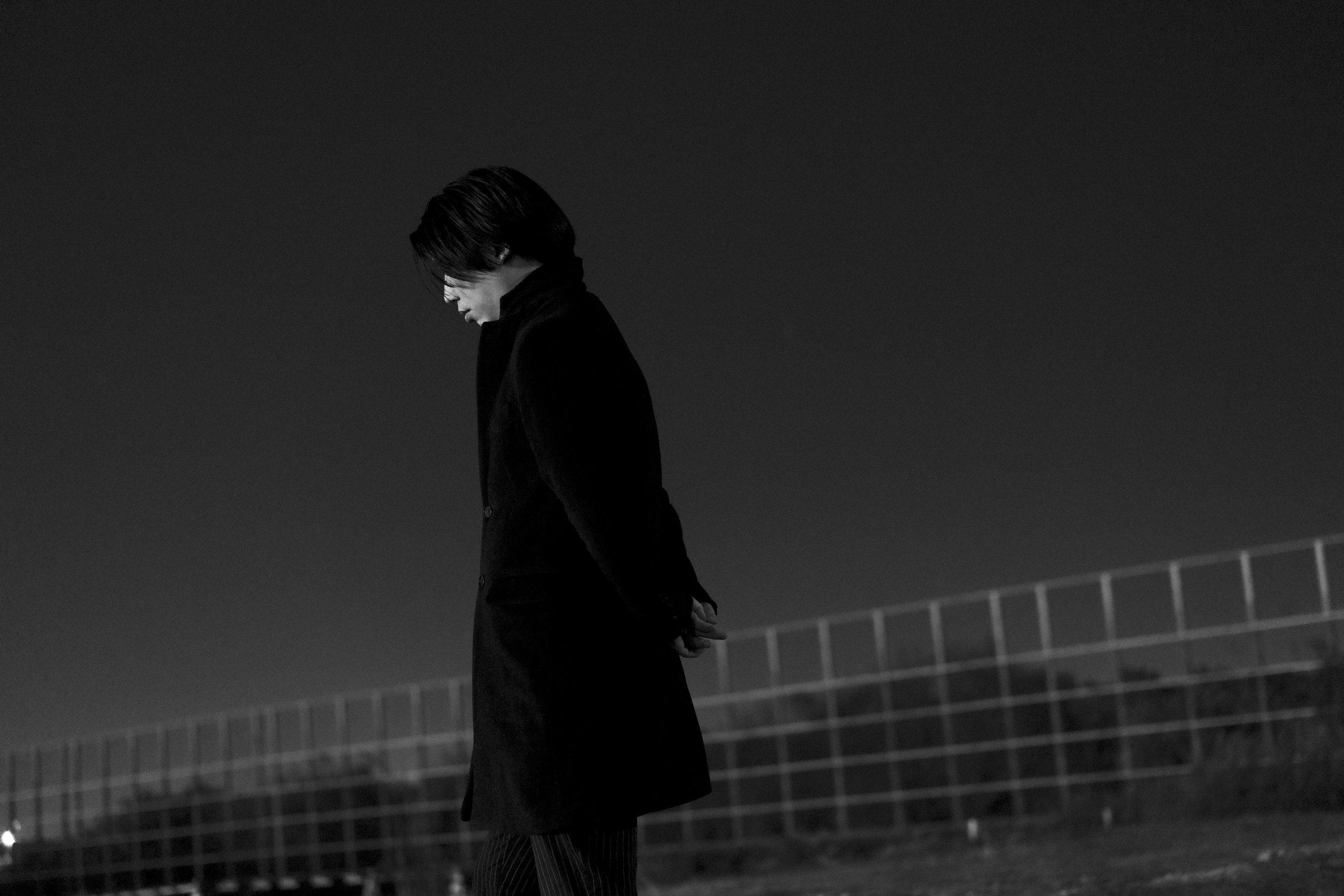 夜の屋外で考え込む男性のシルエット。