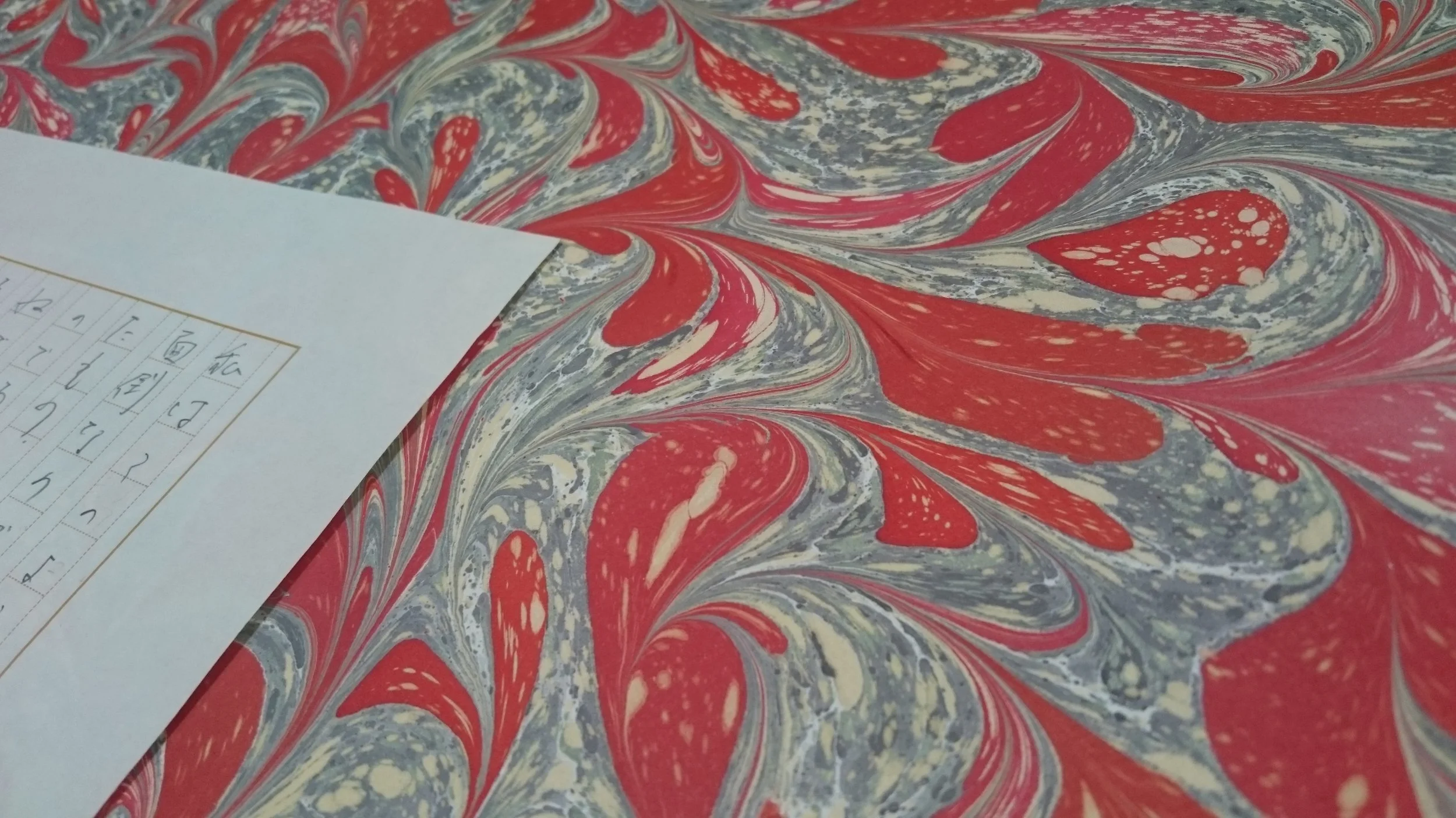 赤と白と青のマーブル模様の紙の上に白い紙が置かれている