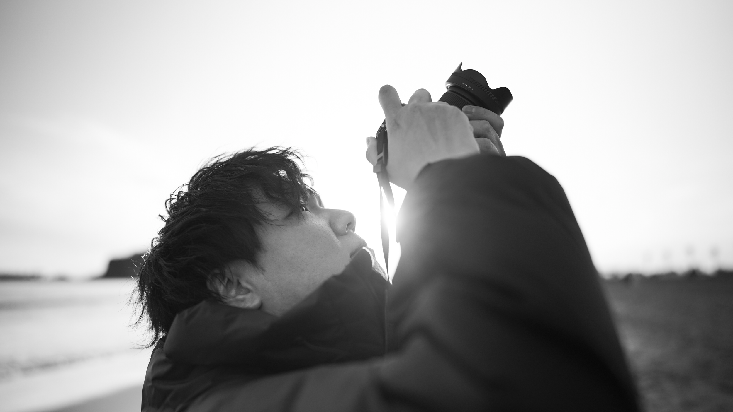 海辺で写真を撮る男性の黒と白の写真。