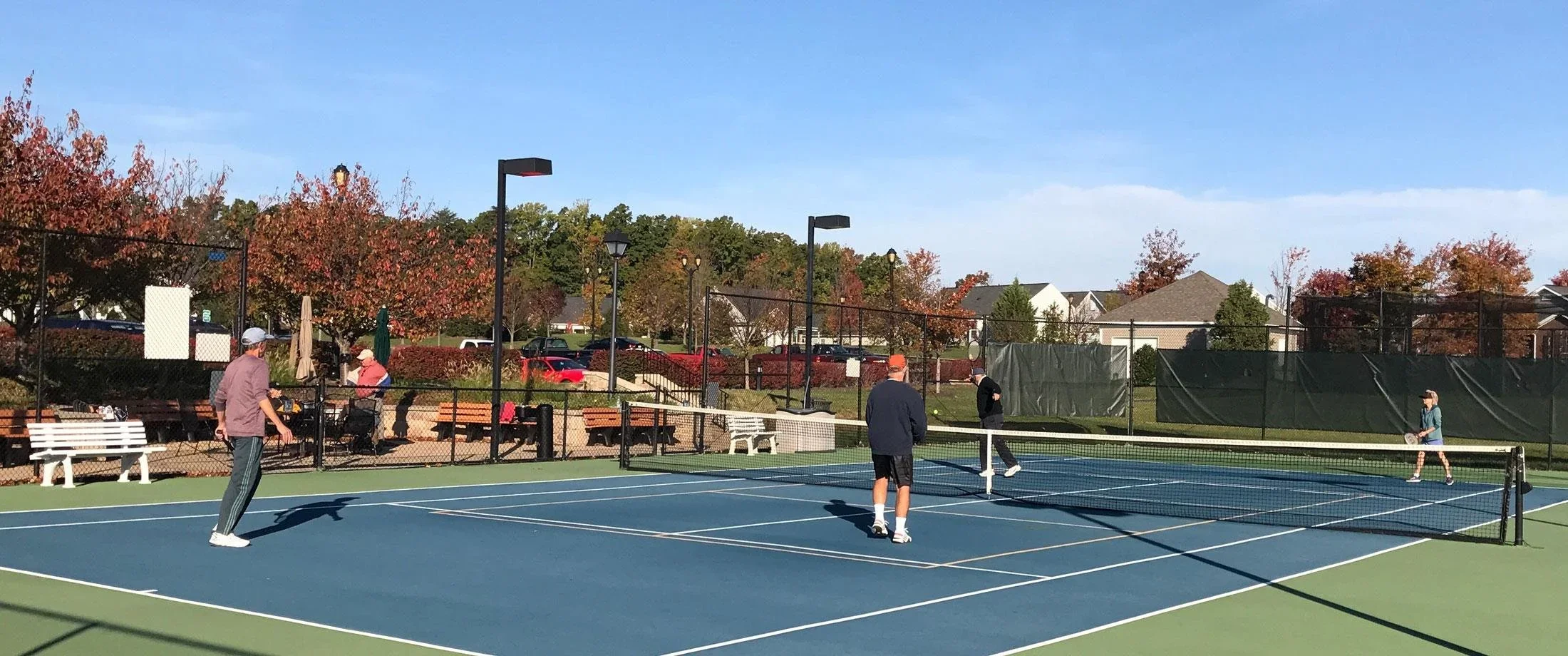 Adults above 55+ playing tennis and pickleball in the  court