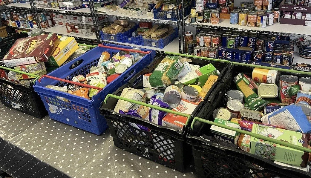 Shopping carts filled with canned and packaged food items in a grocery store aisle.