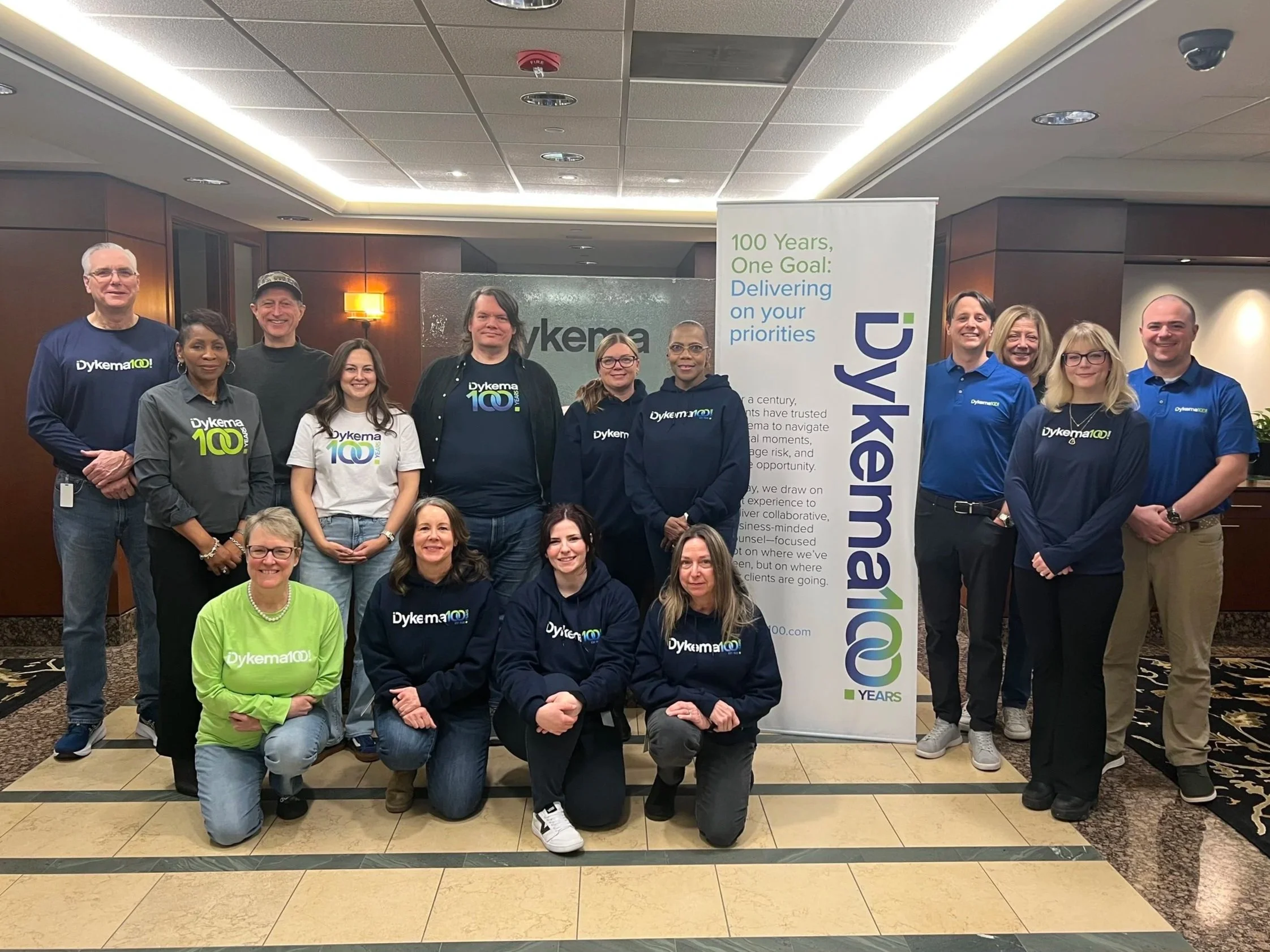 Large group of Dykema staff showing off team swag during the firms centennial kickoff event. 